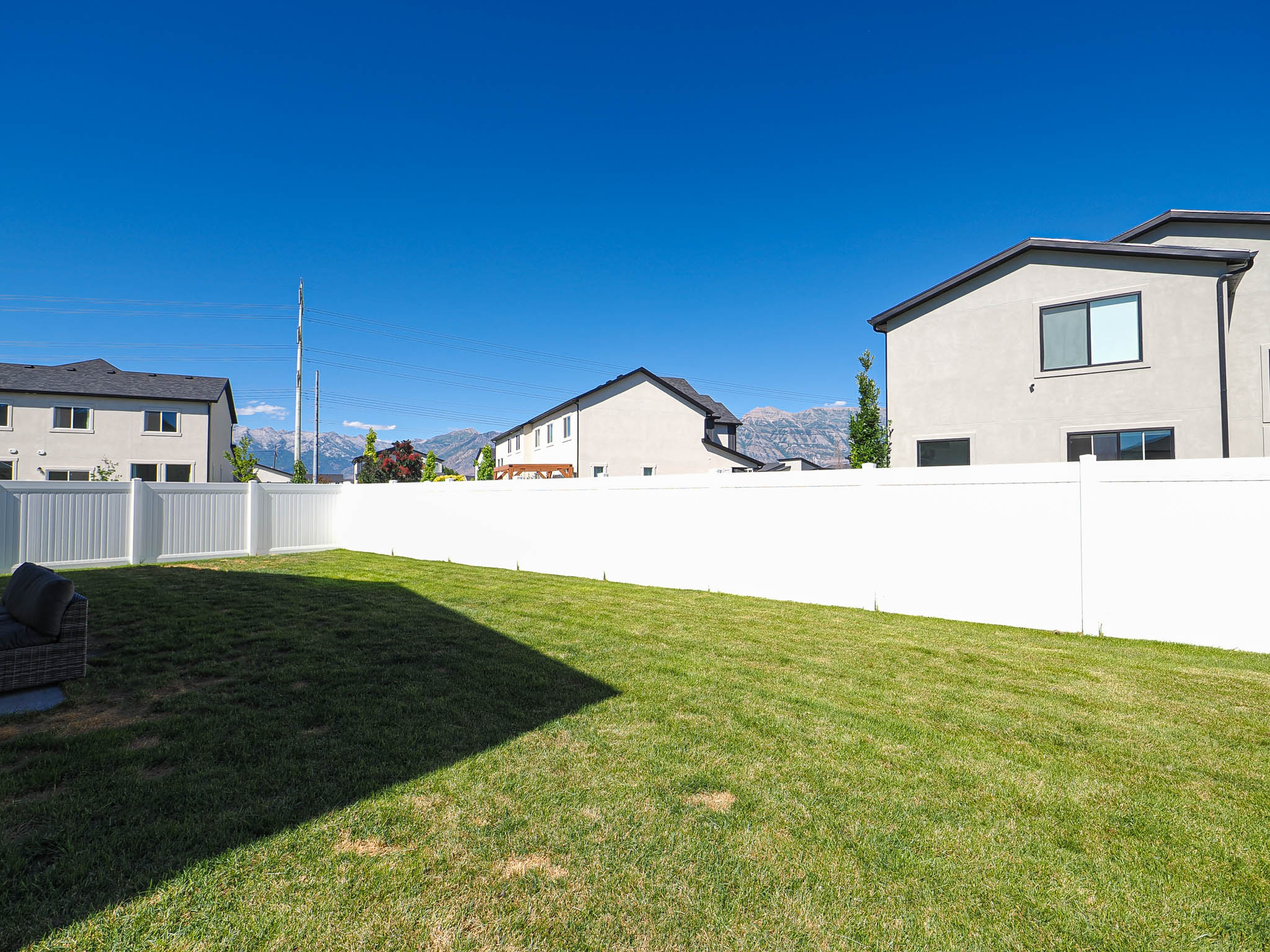 Expansive lawn area enclosed by a white privacy fence