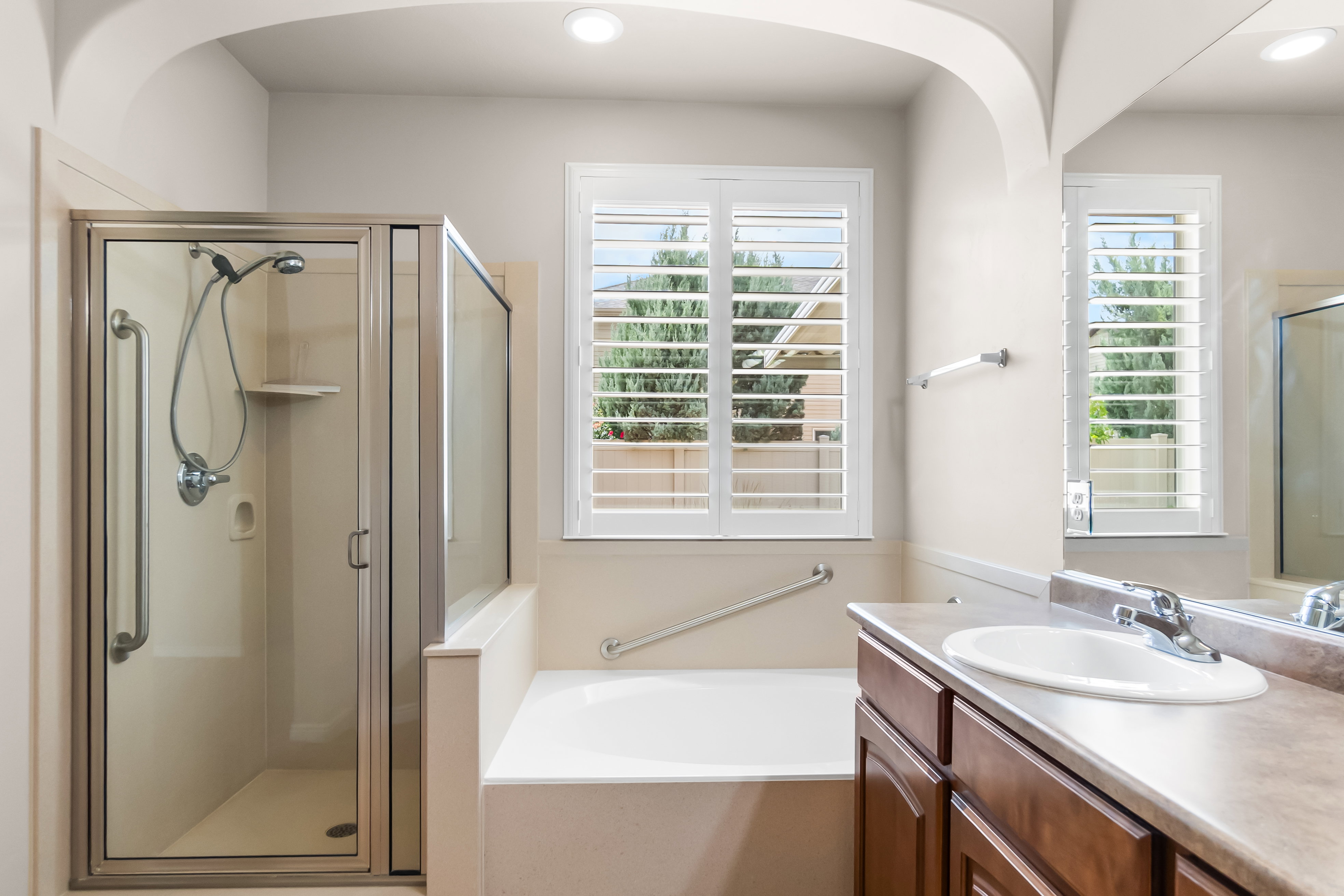 Bathroom featuring a glass-enclosed shower, built-in bathtub, and a vanity with an integrated sink and warm wood-finish cabinetry