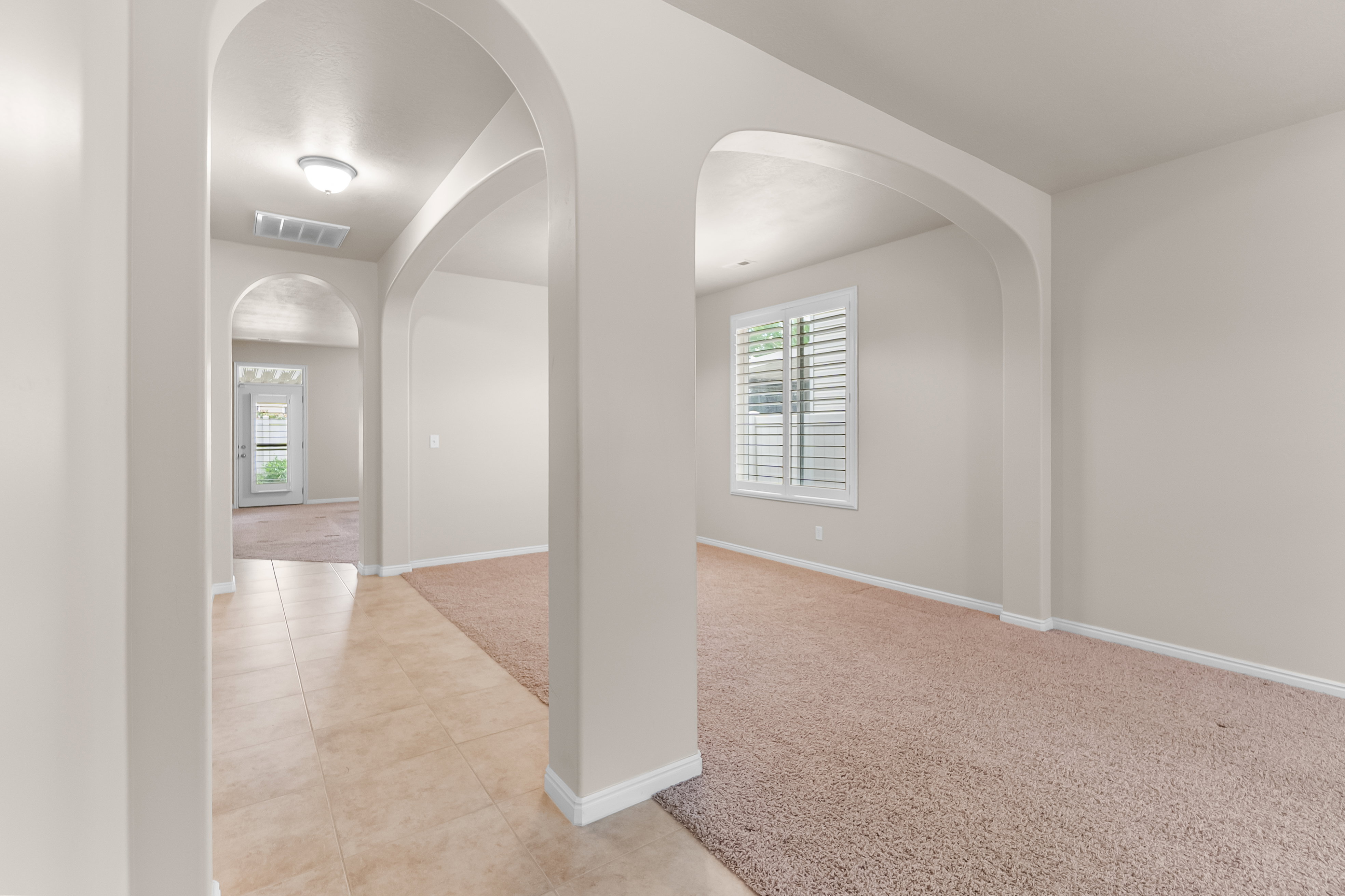 Archways defining interior spaces, light-colored walls, and a window with plantation shutters