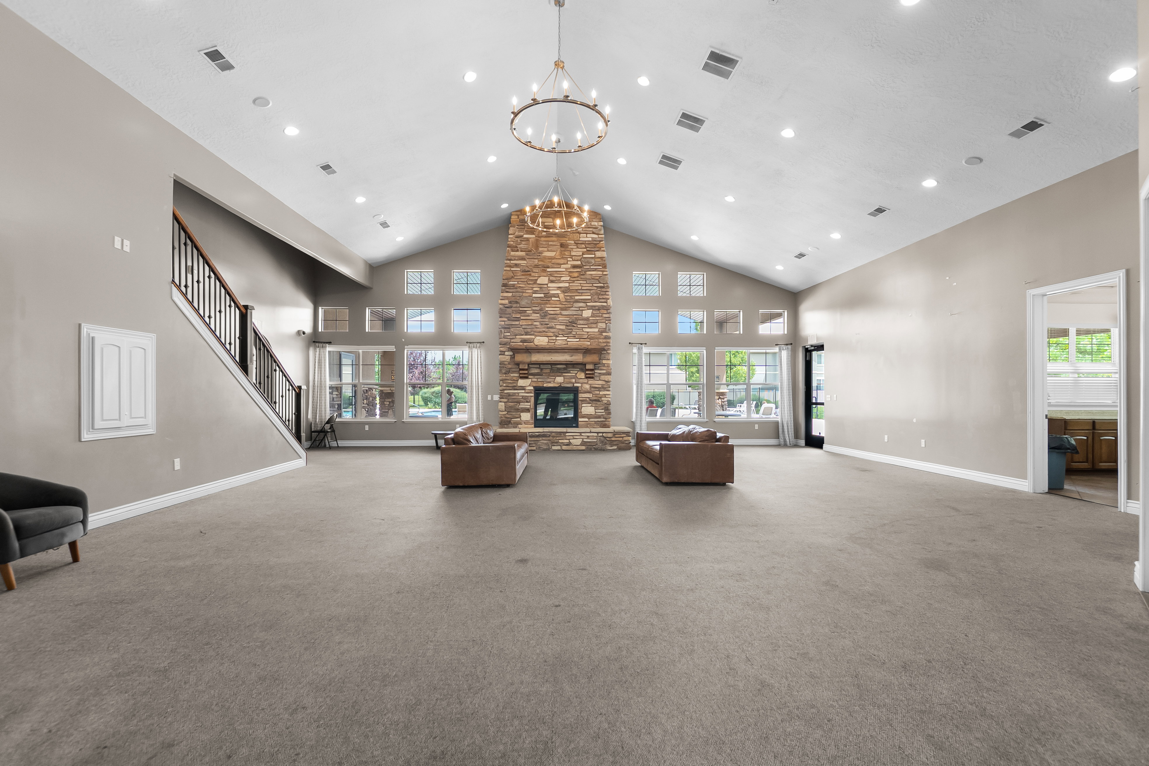 Spacious room featuring a vaulted ceiling with recessed lighting and a large wagon wheel chandelier