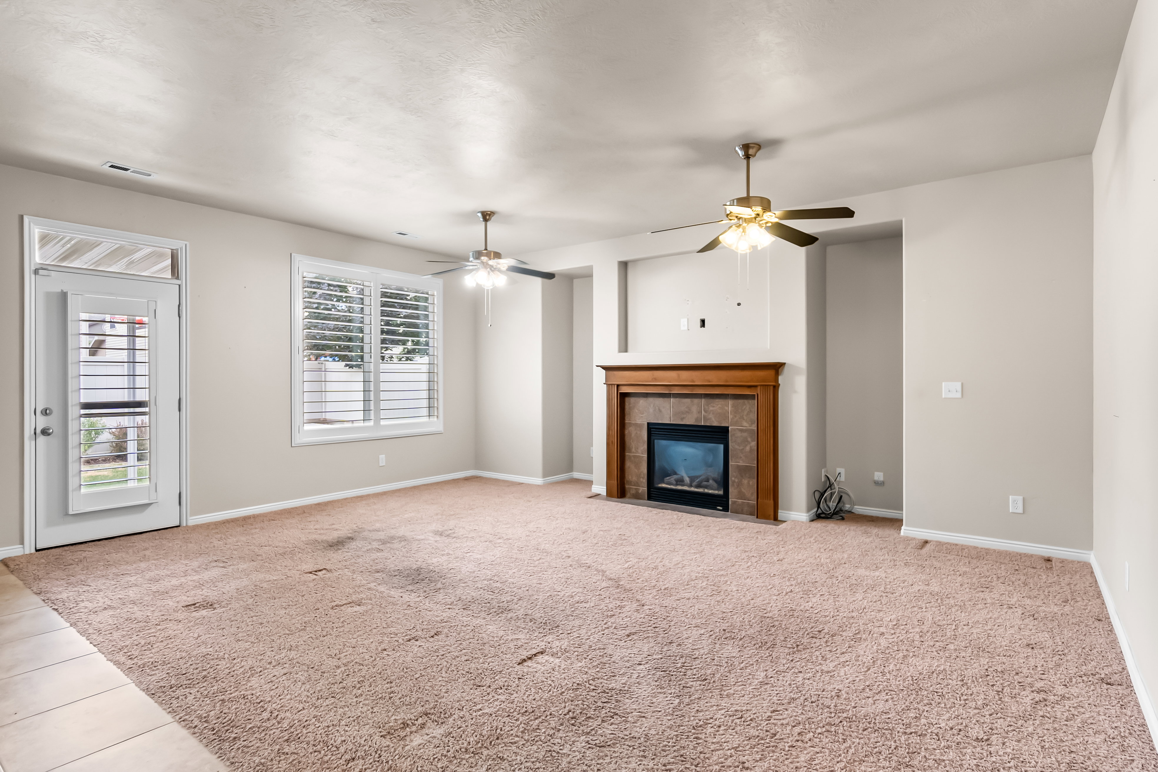 Living room with an electric fireplace featuring a wood mantel and tile surround