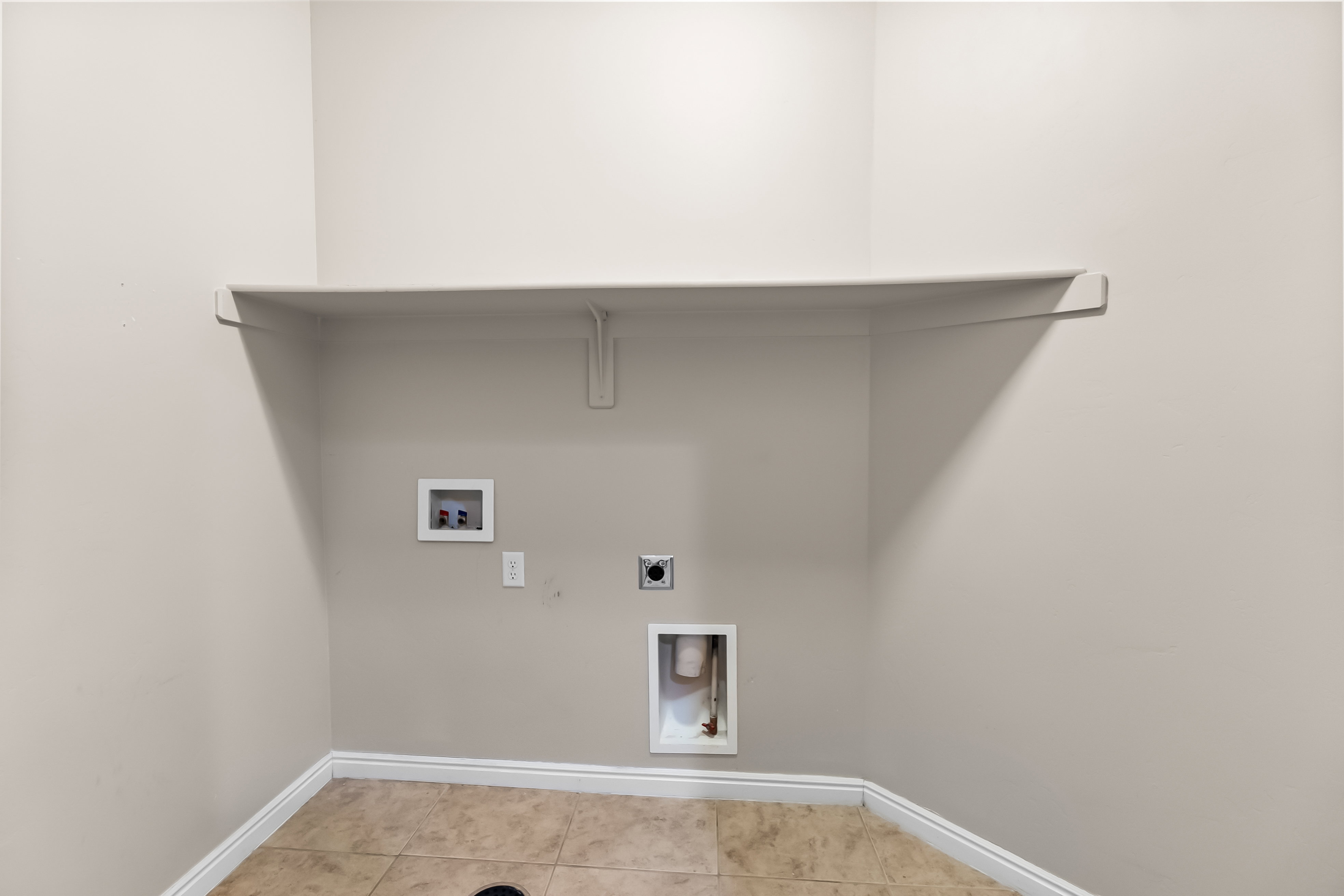 Dedicated laundry area featuring a built-in shelf, neutral wall tones, and ceramic tile flooring