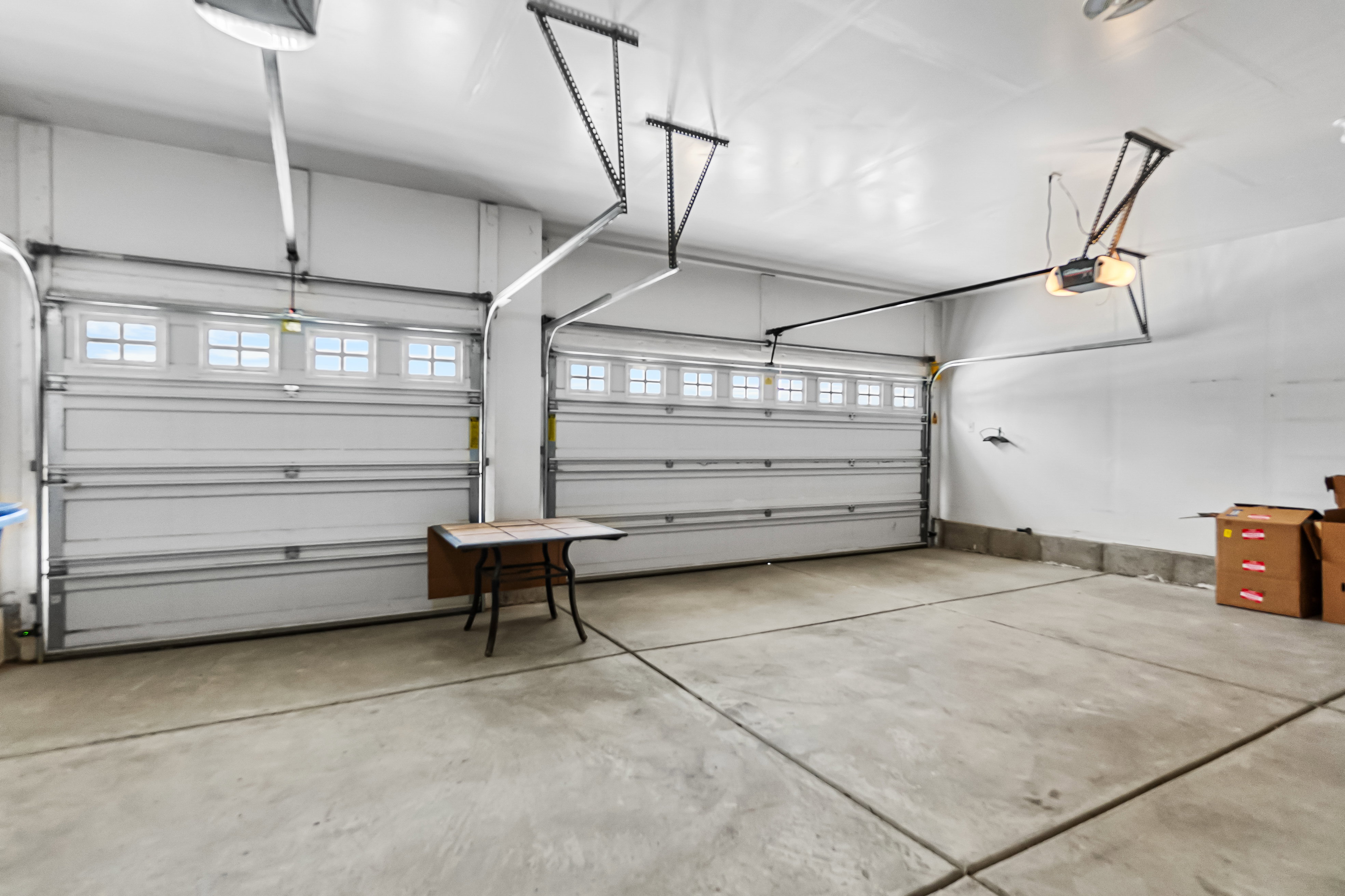 Two-car garage featuring concrete flooring, white walls, and two overhead garage doors with window inserts