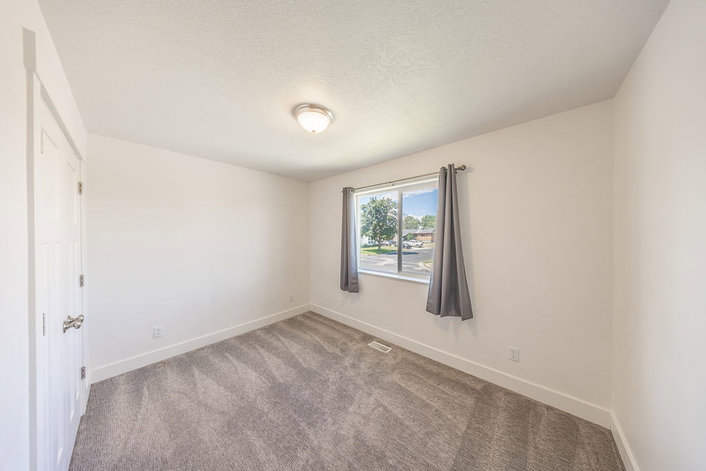 Bedroom #3.  Light wall color.  Light carpet.  Natural light through window.