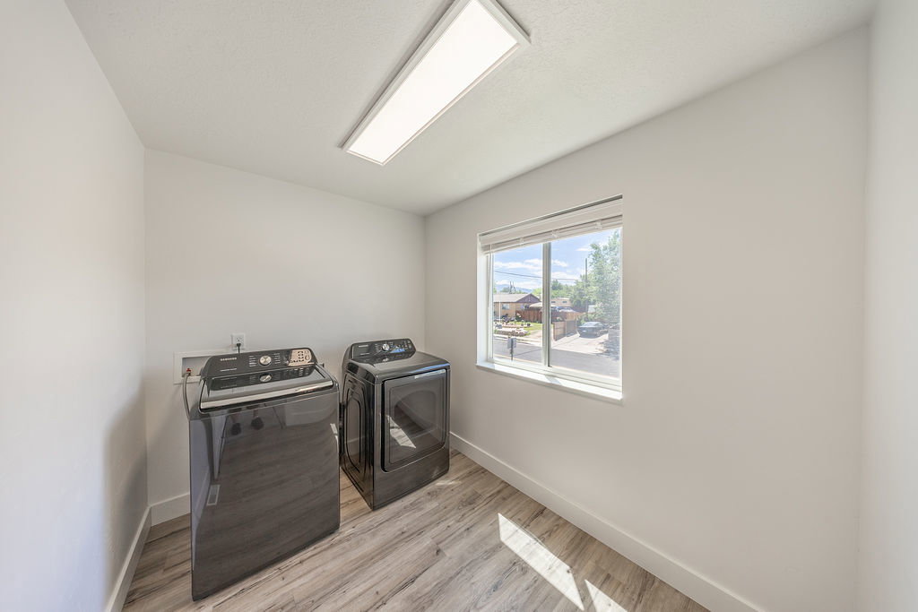 LARGE laundry room with LVP flooring, a window with blinds, and a ceiling-mounted rectangular light fixture