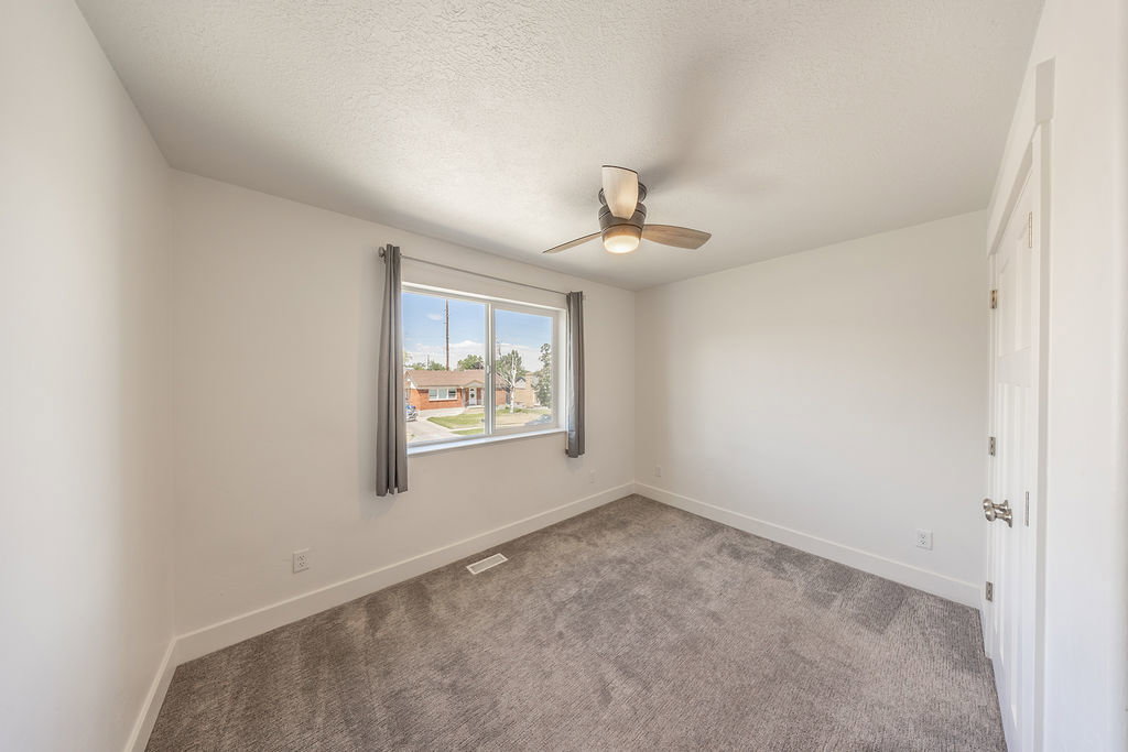 Bedroom #2.  Ceiling fan.  Light colored carpeting.  Closet doors on right.  White walls.