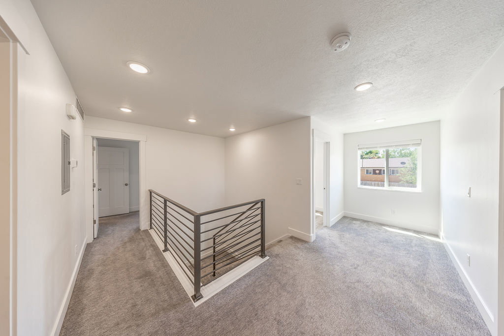 Hallway.  Flex space to the right by window. Light grey carpet.  Natural light.  Recessed lighting.
