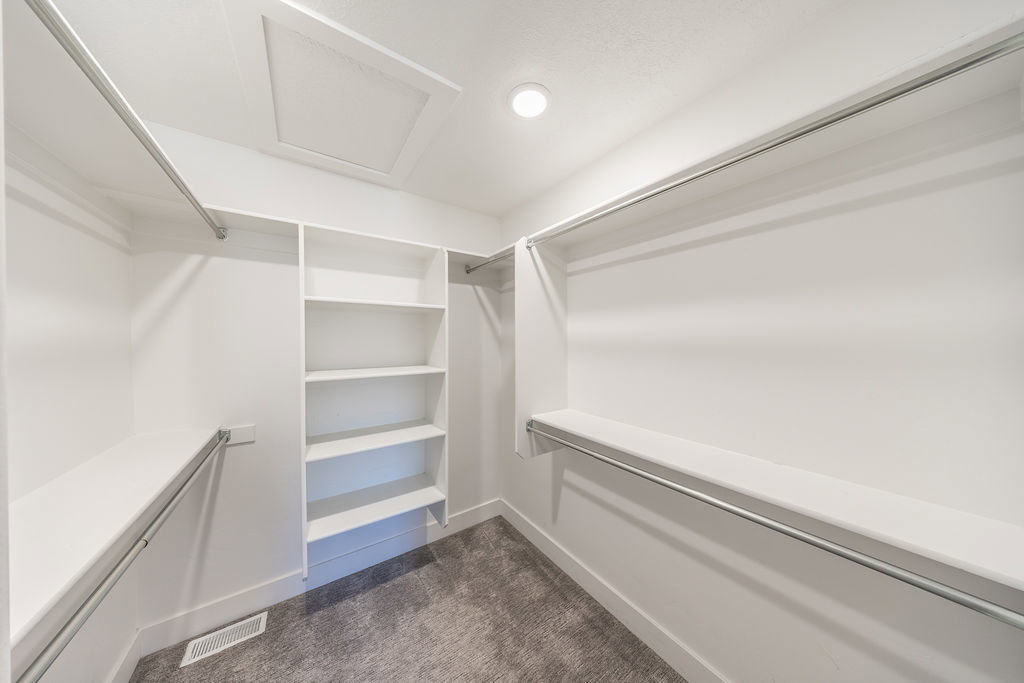 Walk-in closet featuring built-in shelving, multiple hanging rods, and recessed lighting