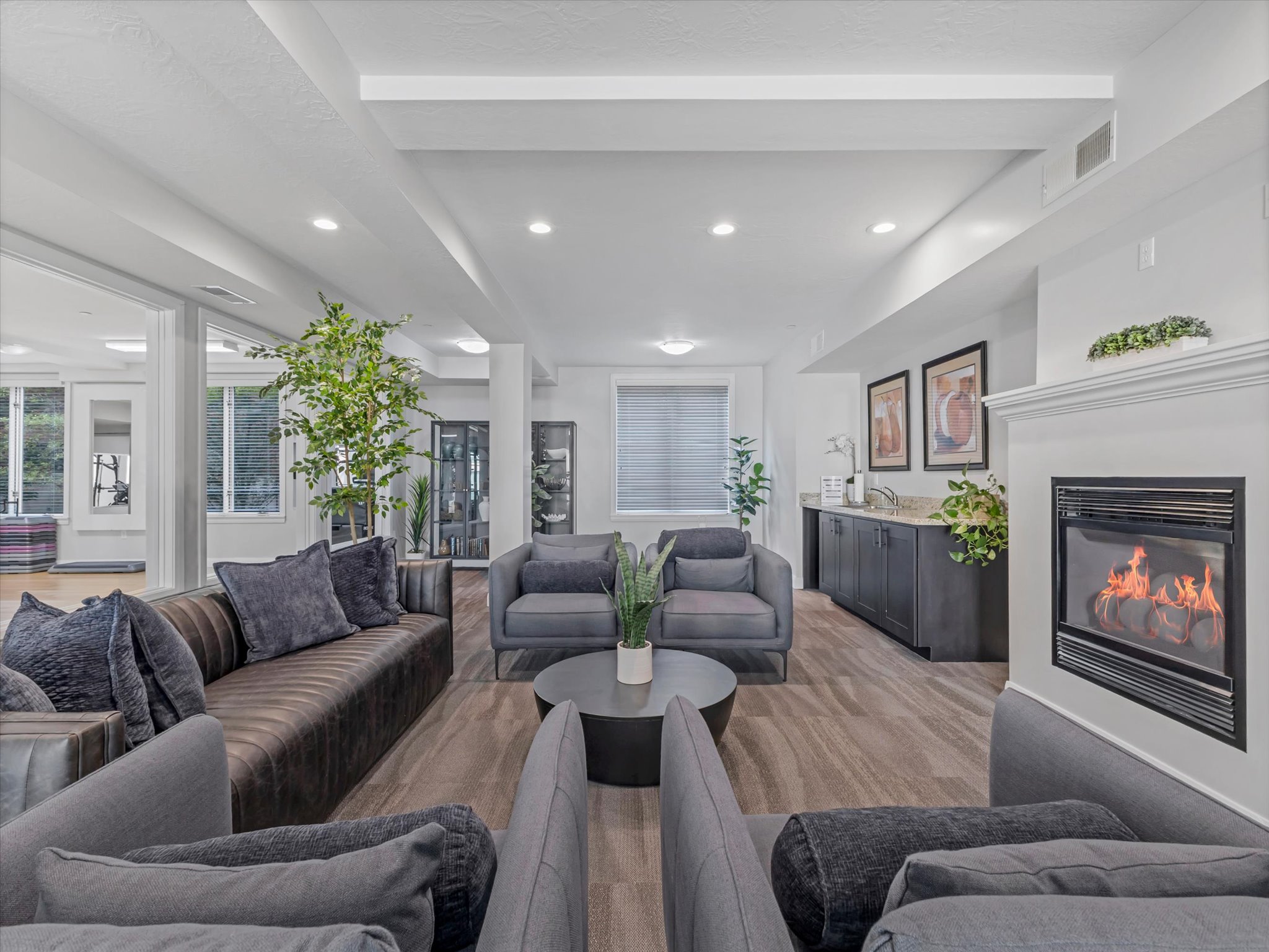 Spacious gathering area featuring wood-finish flooring, recessed lighting, and a white mantel with an inset fireplace