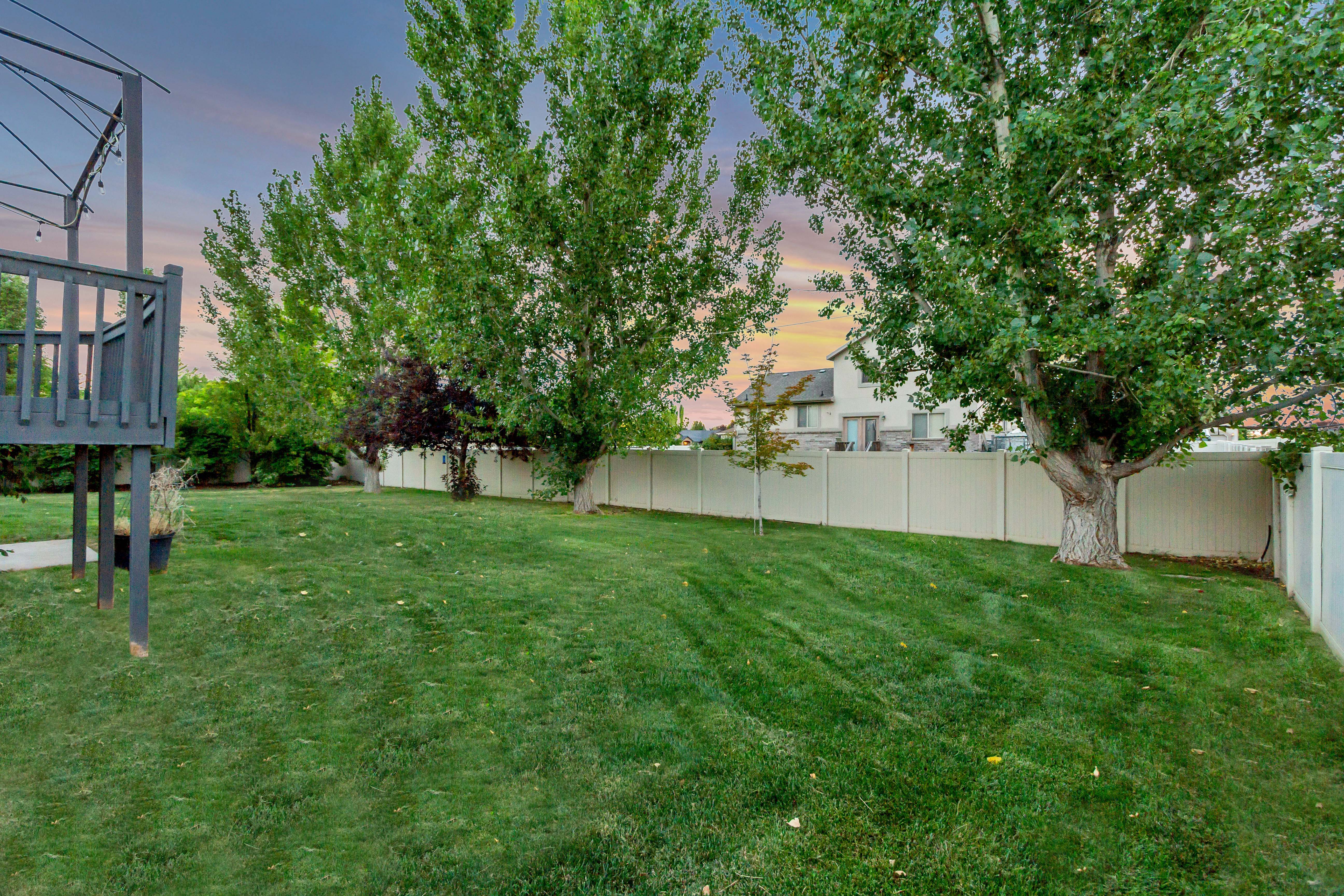 Expansive backyard featuring a manicured lawn, mature trees, and a privacy fence
