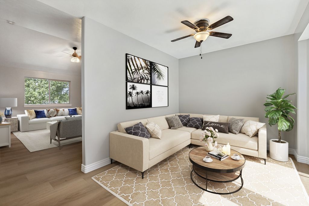 Open-concept living area featuring light gray walls, wood-finish flooring, and white baseboards