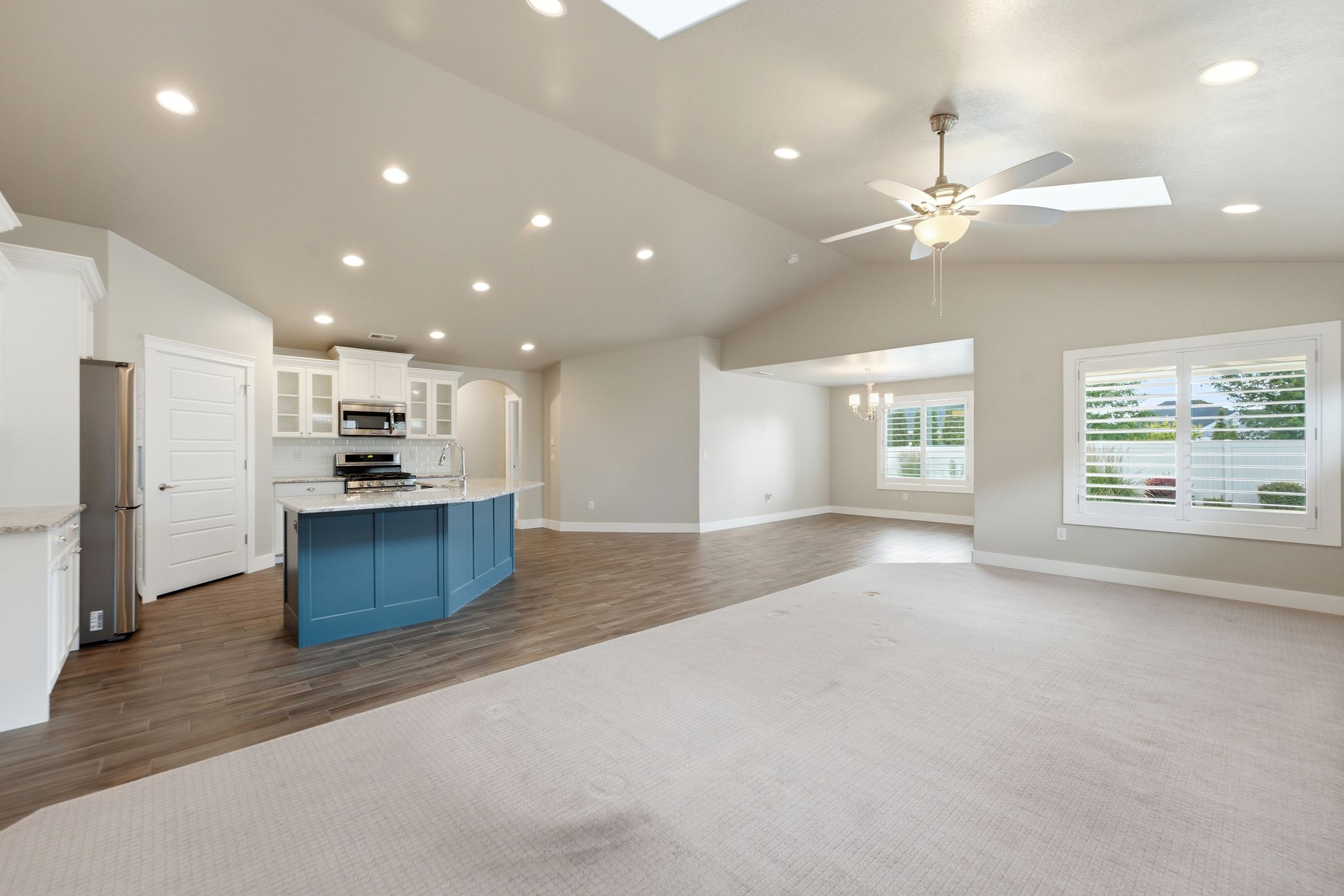 Bright open-concept living area featuring vaulted ceilings, recessed lighting, and a modern ceiling fan