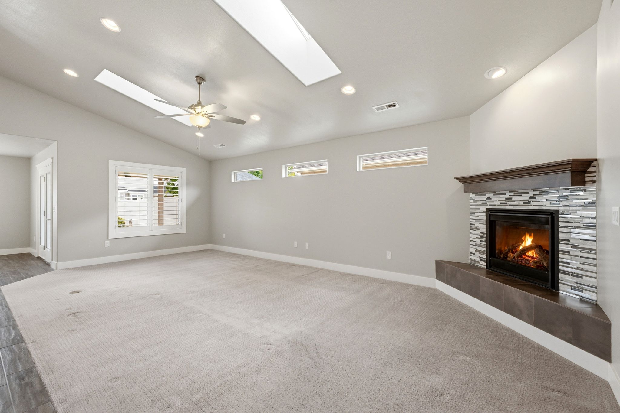 Spacious room featuring a corner fireplace with mosaic tile surround, a dark wood mantel, and an elevated hearth