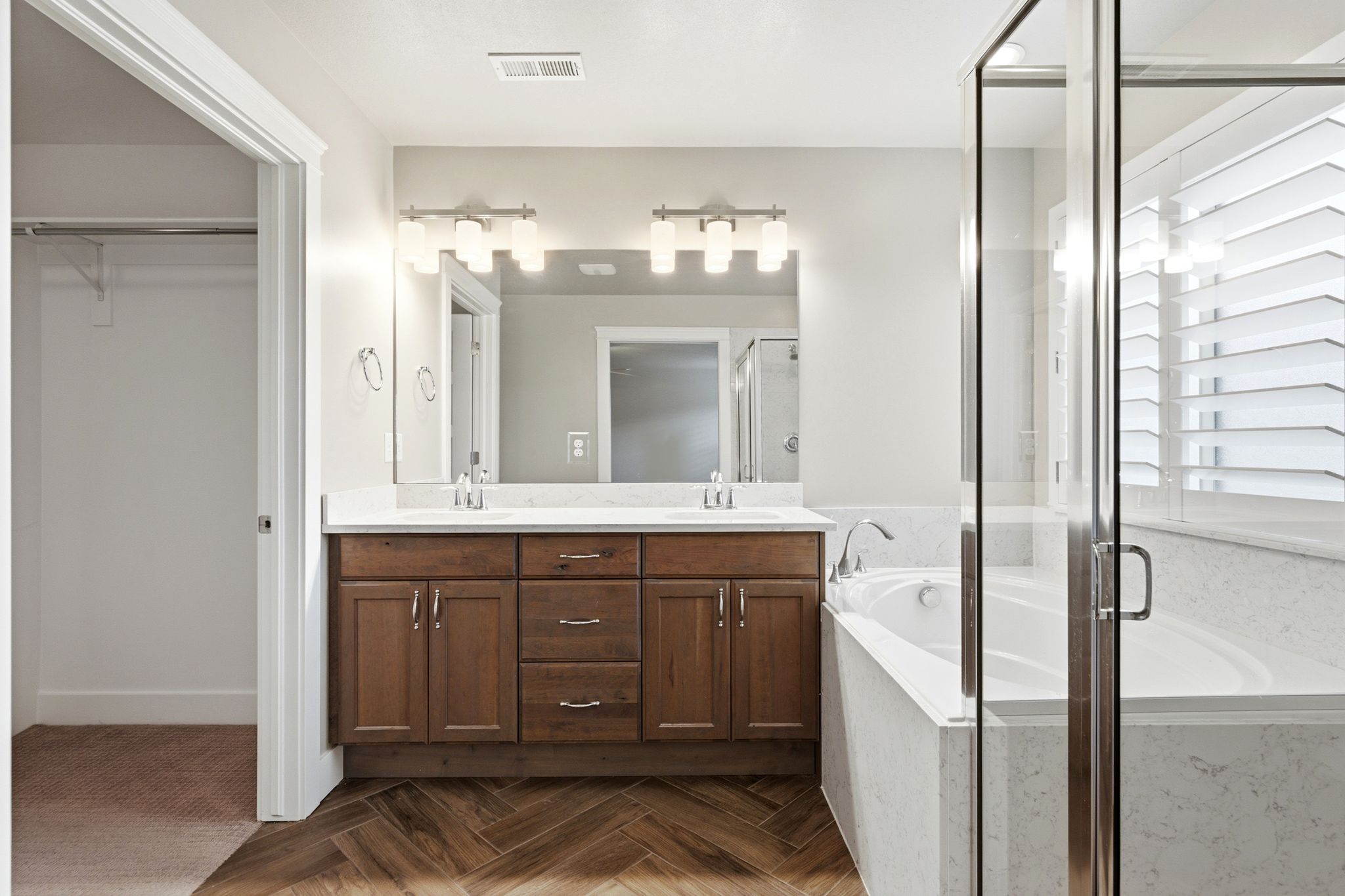 Bathroom featuring a dual vanity with a light-toned countertop, wood cabinetry, and individual rectangular mirrors
