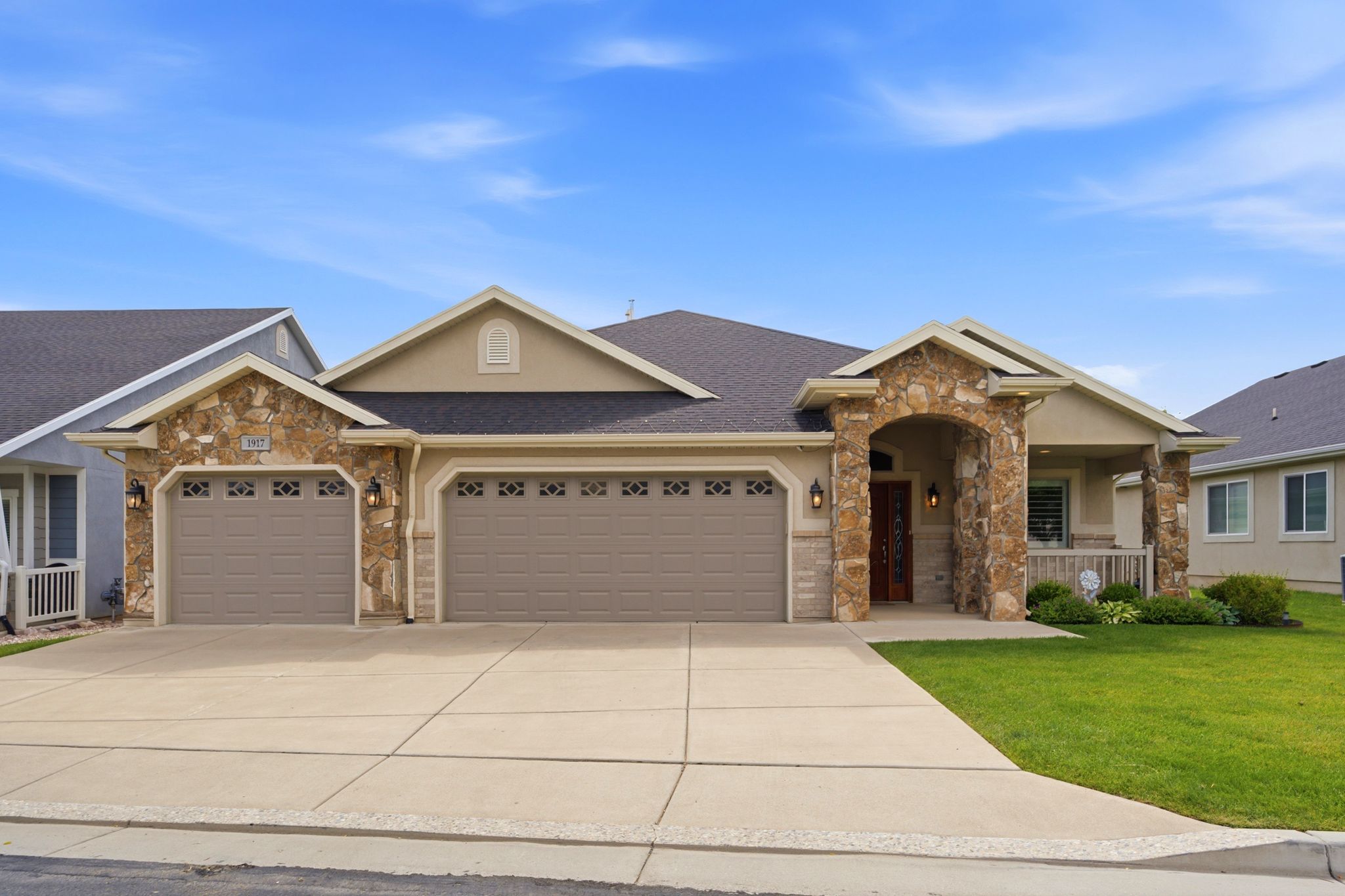 Stucco exterior with stone accents and dark shingle roofing
