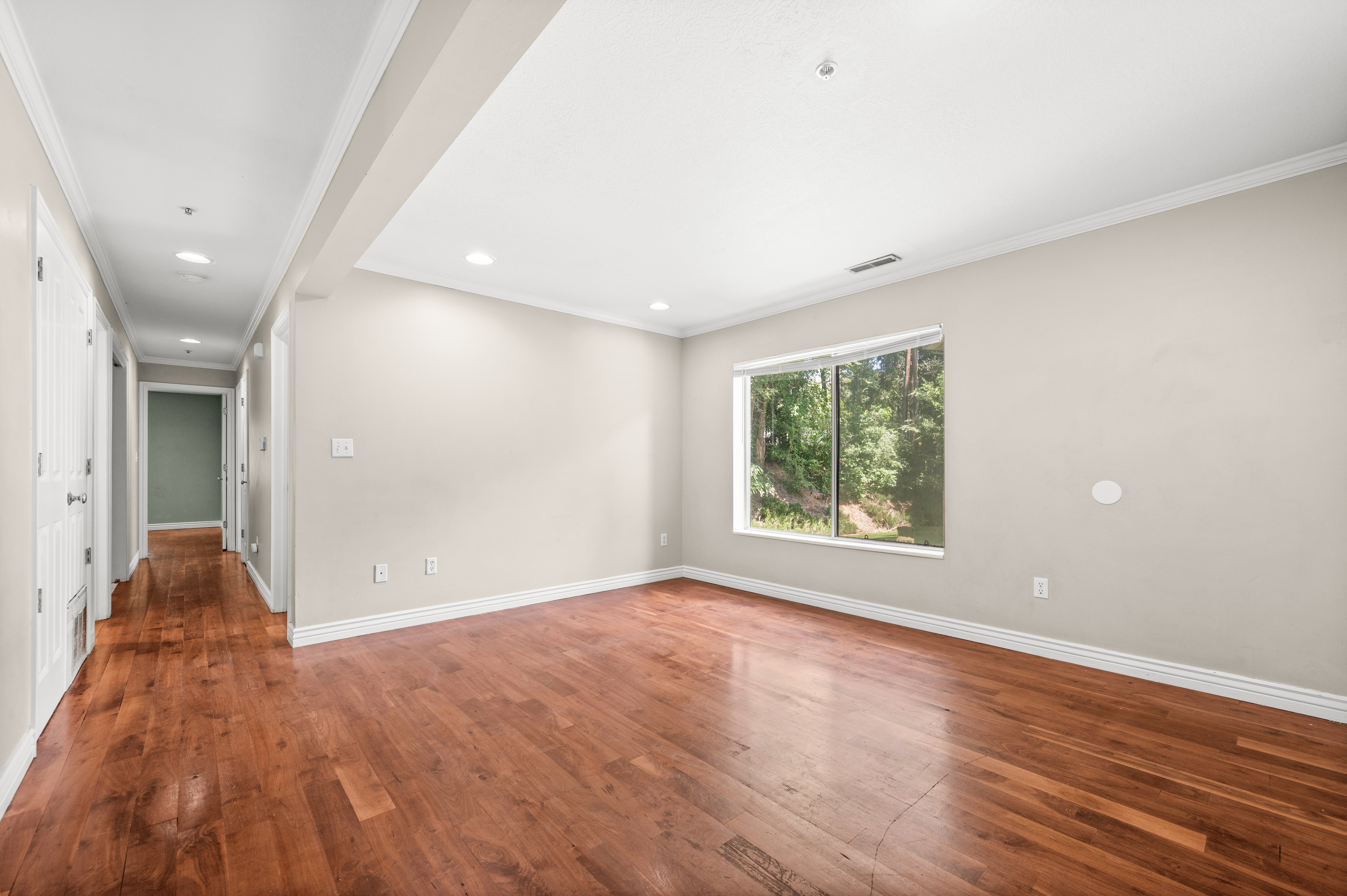 Hardwood flooring throughout, recessed lighting, crown molding, and a large window overlooking natural scenery