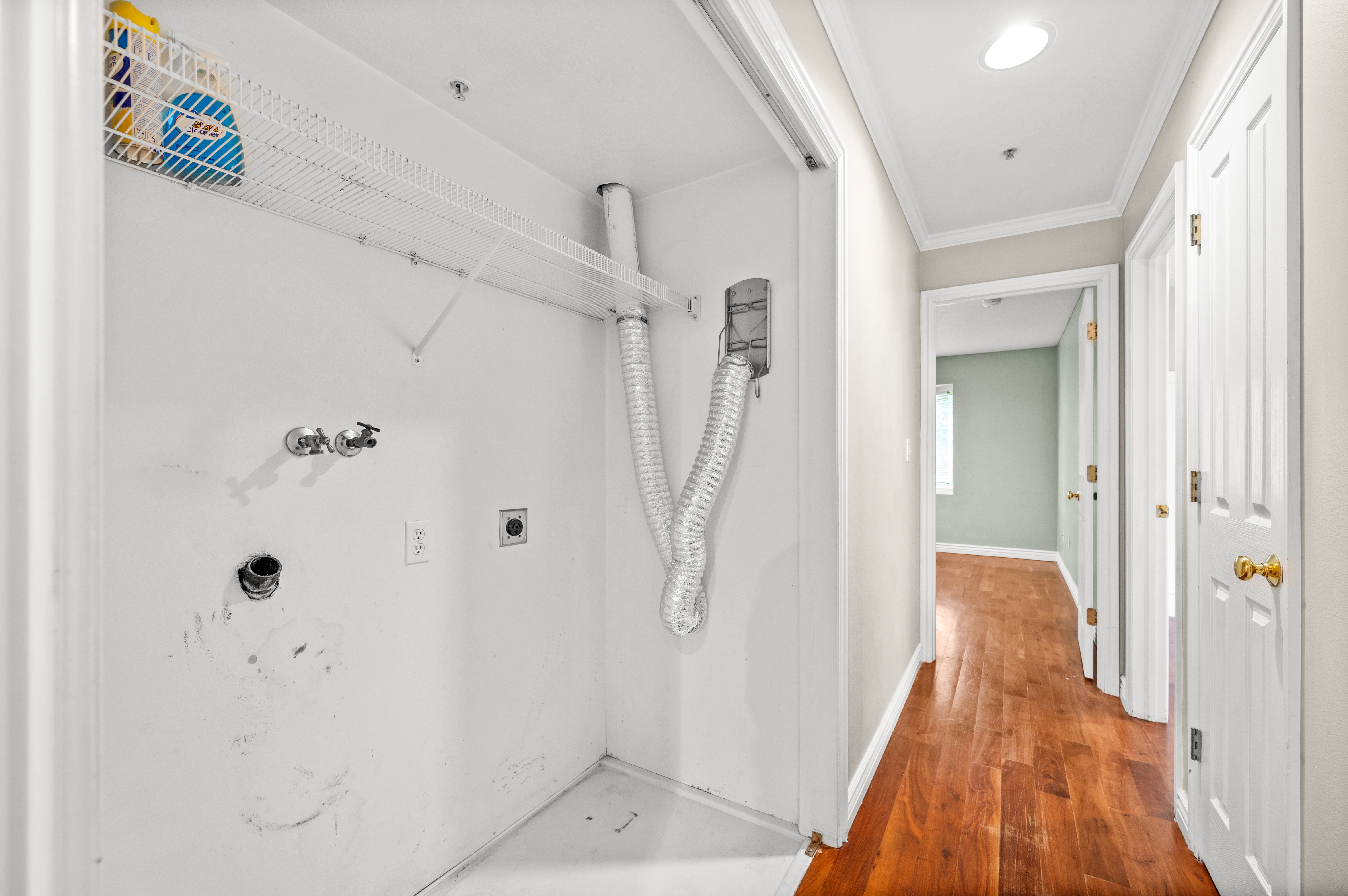 Dedicated laundry closet featuring hookups for washer and dryer, an overhead wire shelving unit, and a dryer vent