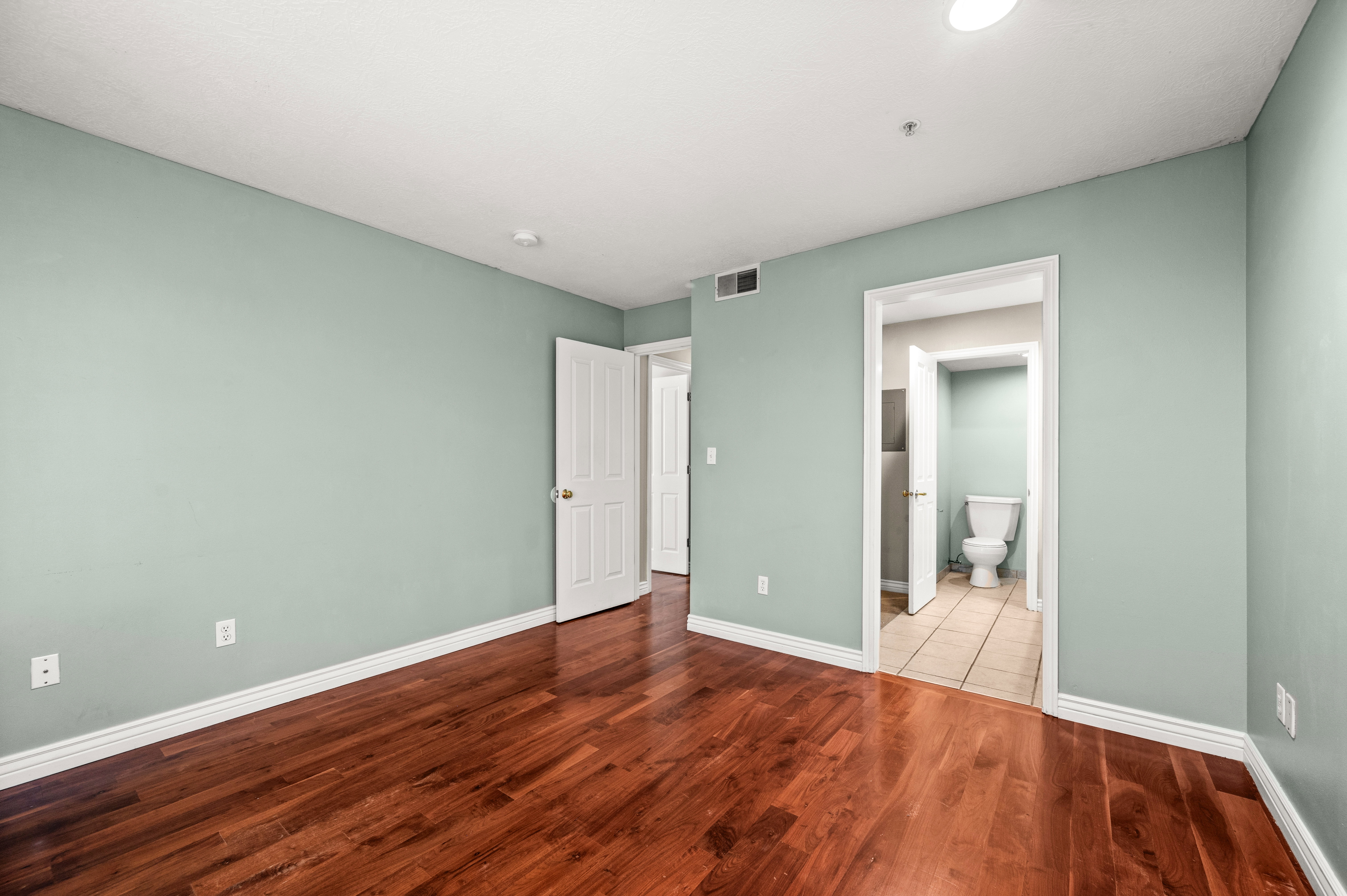 Room featuring wood-finish flooring, light blue-green wall paint, white trim, and a white ceiling with recessed lighting