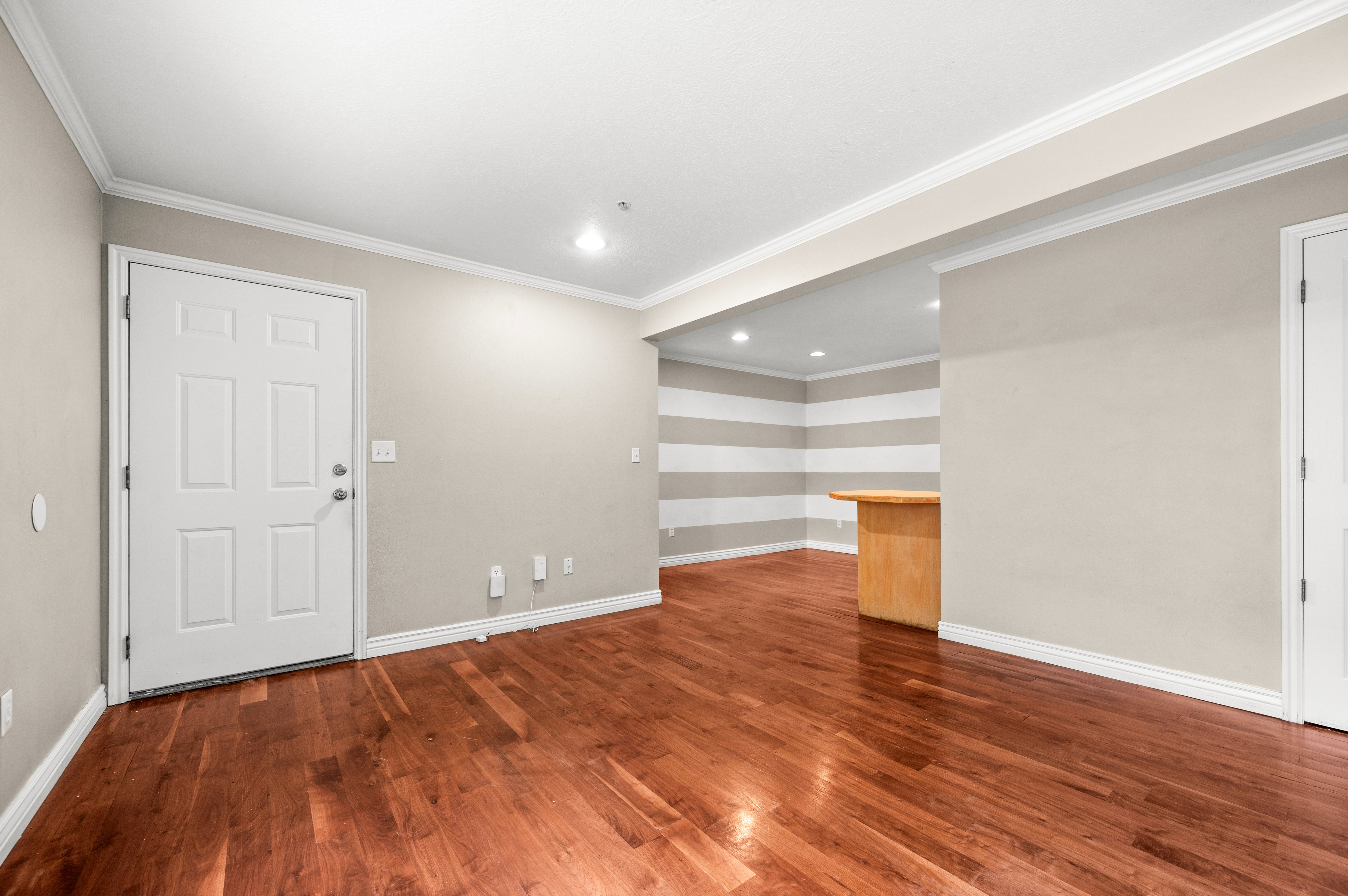 Open living area featuring rich wood-finish flooring, recessed lighting, and crown molding