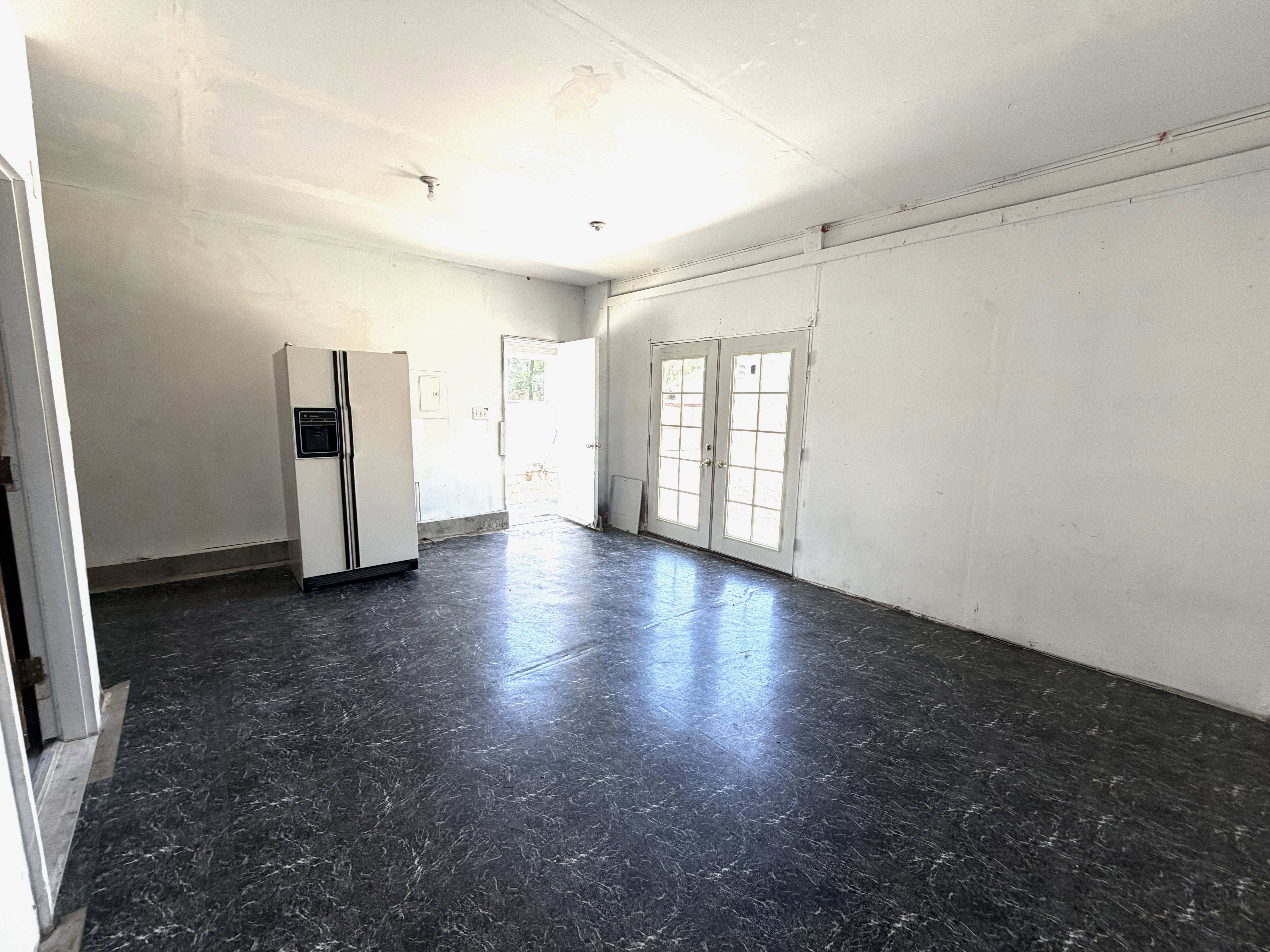 Spacious room featuring patterned flooring, white painted walls, and a white ceiling