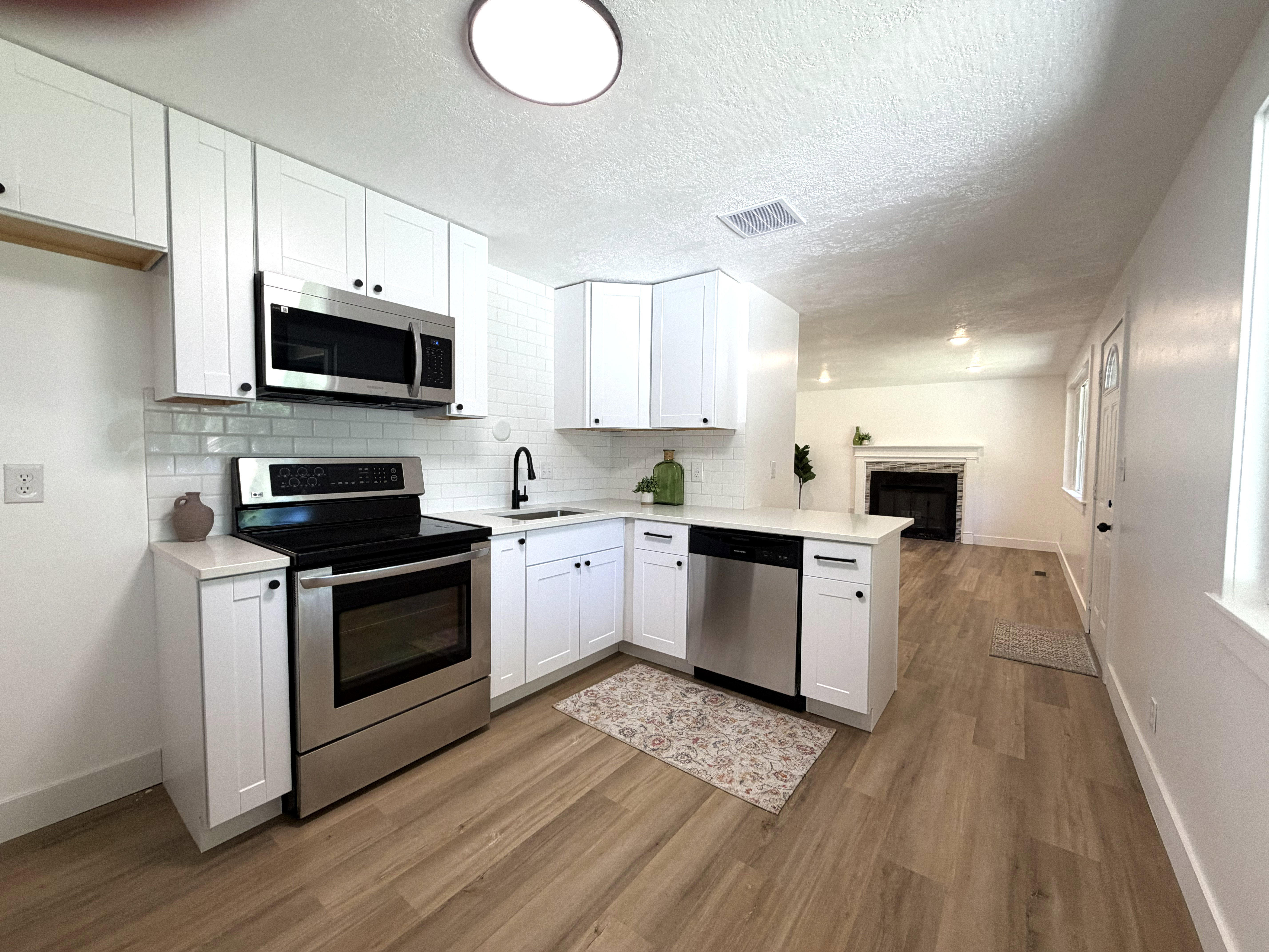 Modern kitchen featuring white cabinetry, subway tile backsplash, stainless steel appliances, and wood-finish flooring