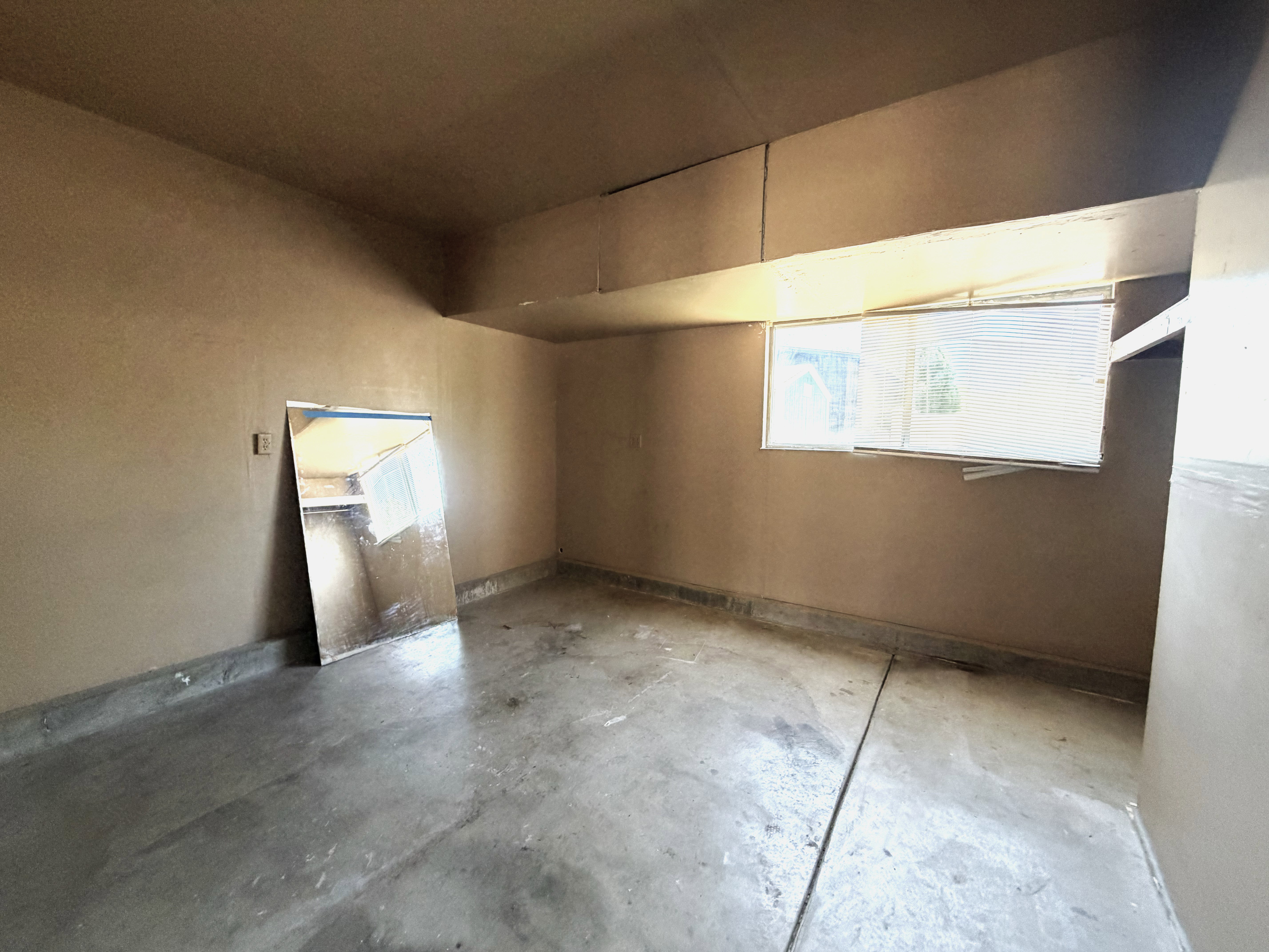 Room featuring concrete flooring, neutral-toned walls, and a window with horizontal blinds