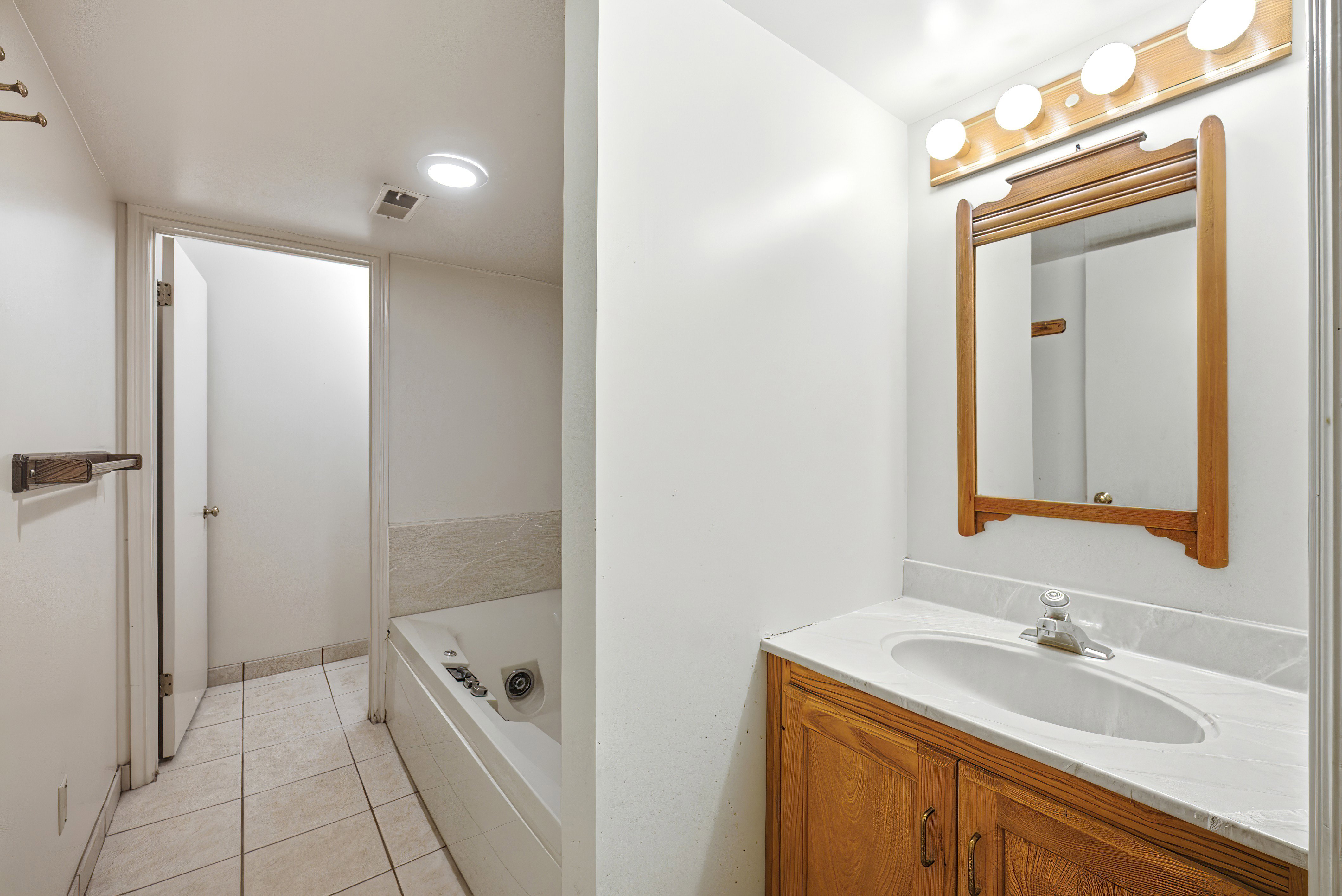 Bathroom vanity with a wood-finish cabinet, a white oval undermount sink, and a light-colored countertop