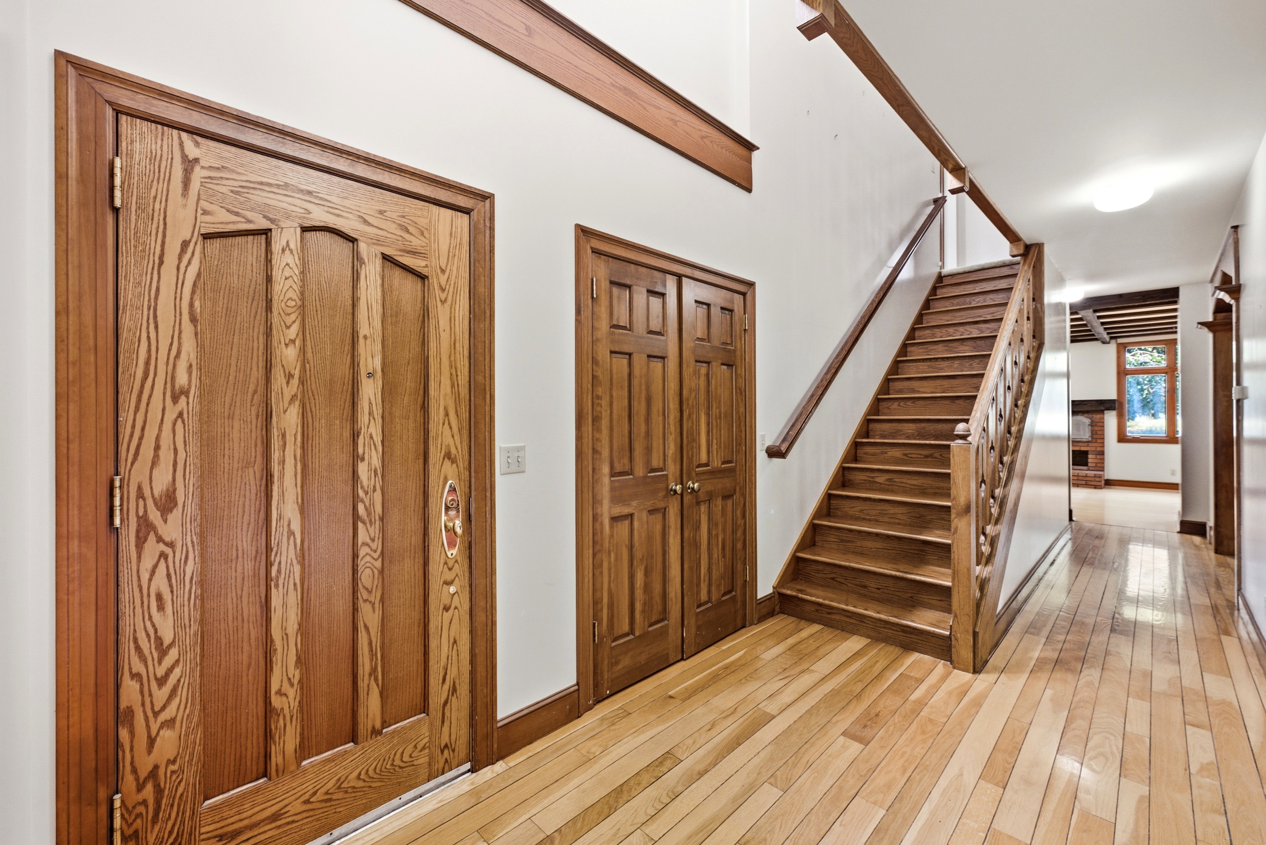 Hardwood flooring extending throughout the entryway and visible rooms, featuring a prominent wooden staircase with matching railings