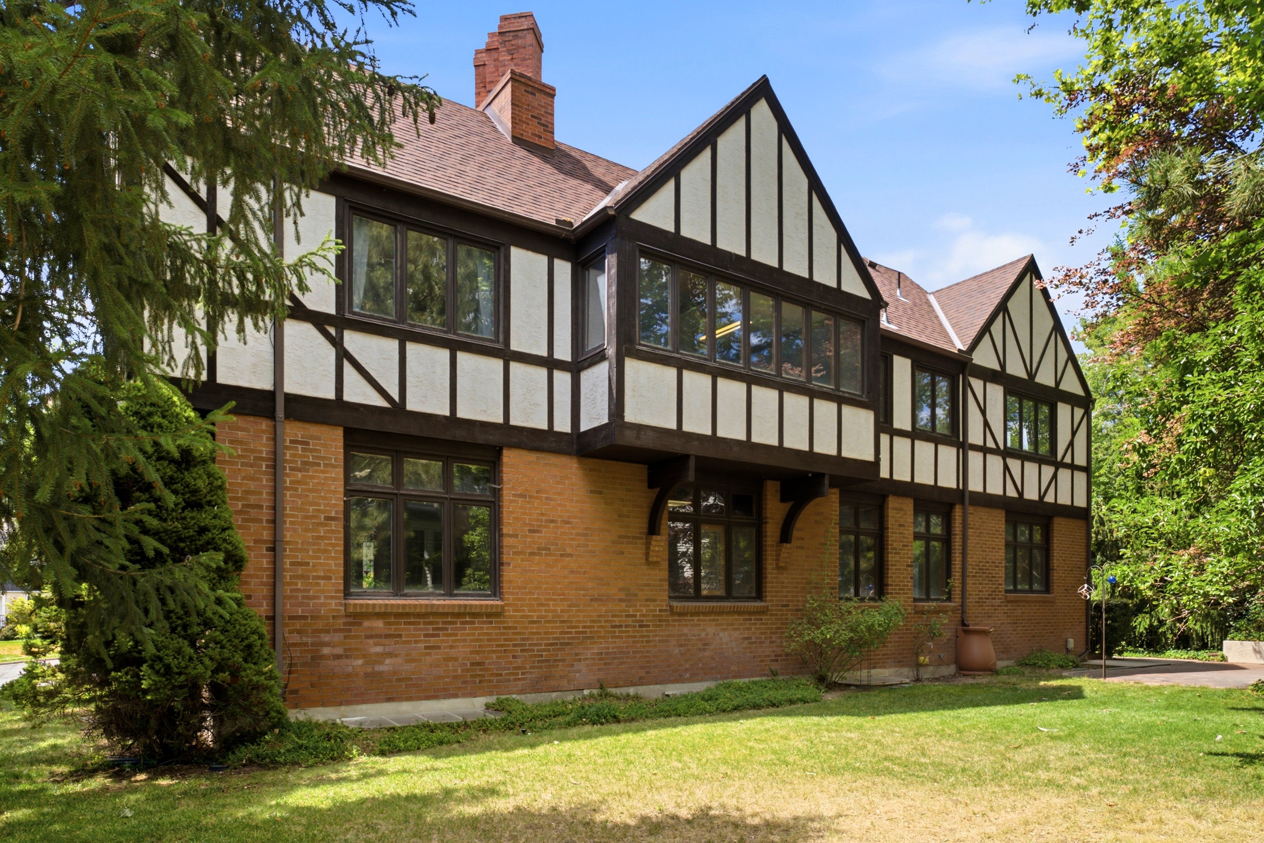 Tudor-style residence featuring a brick facade, exposed timber framing, multiple gables, and a prominent chimney