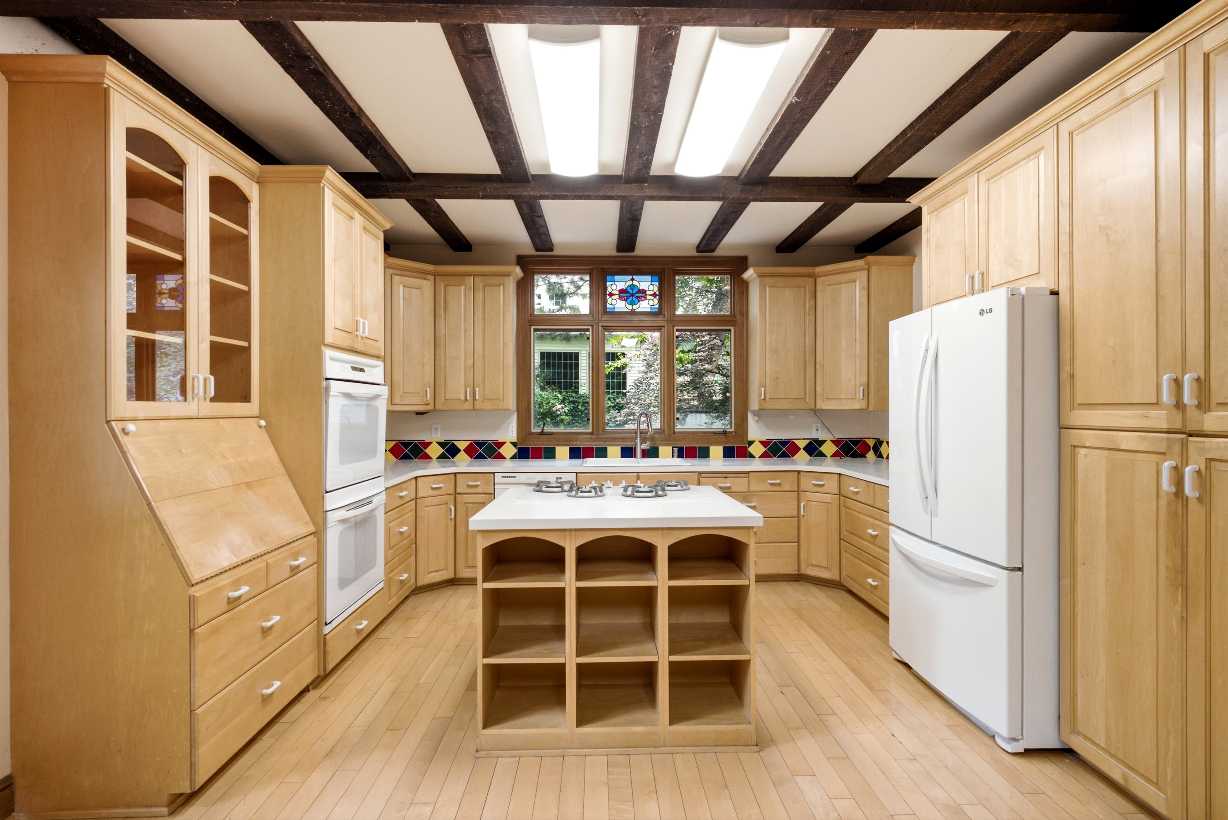 Kitchen featuring light wood cabinetry, exposed ceiling beams, and wood-finish flooring
