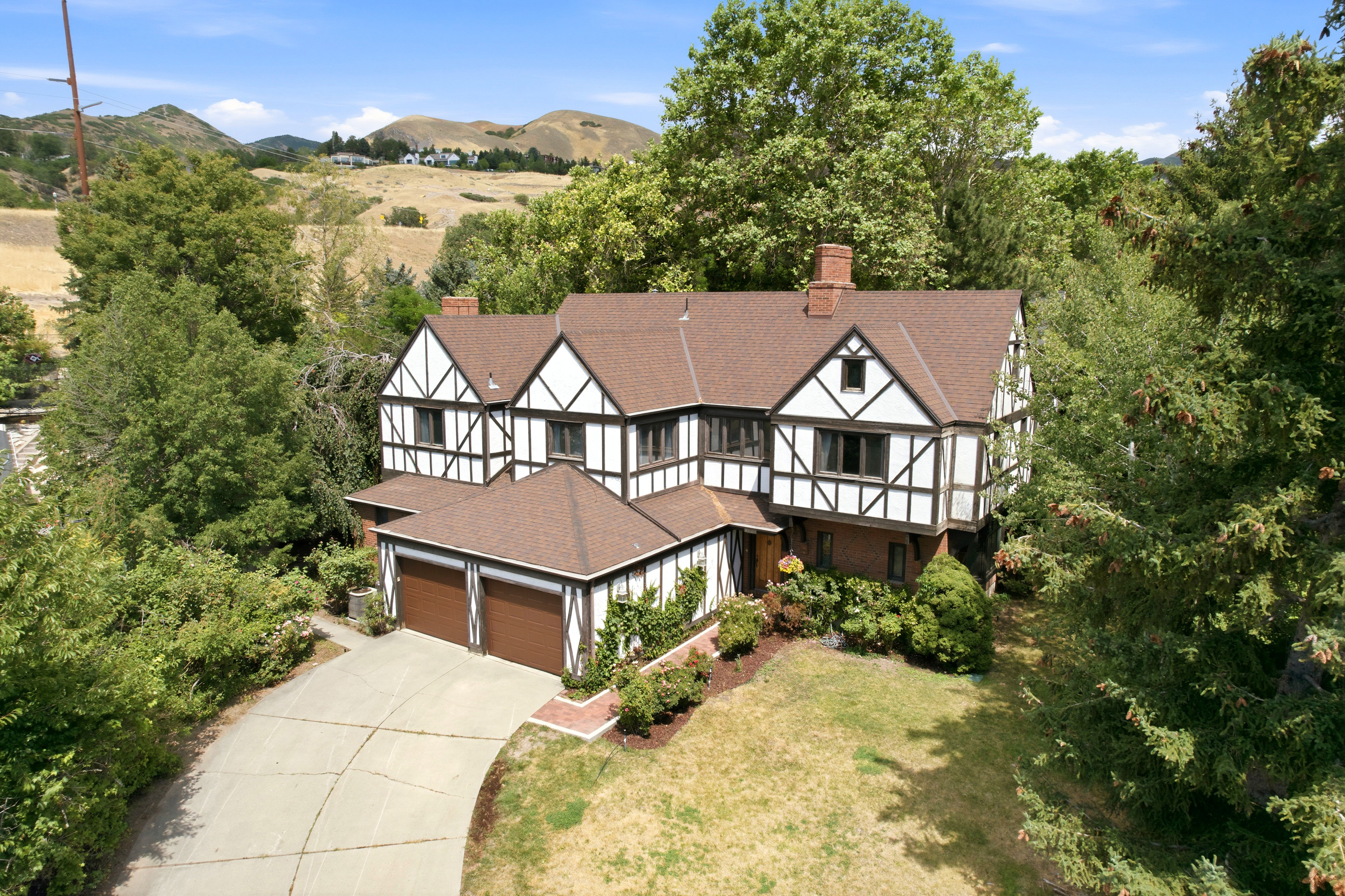 Tudor-style residence featuring a prominent brown shingle roof, white and dark brown half-timbering, and a brick lower facade
