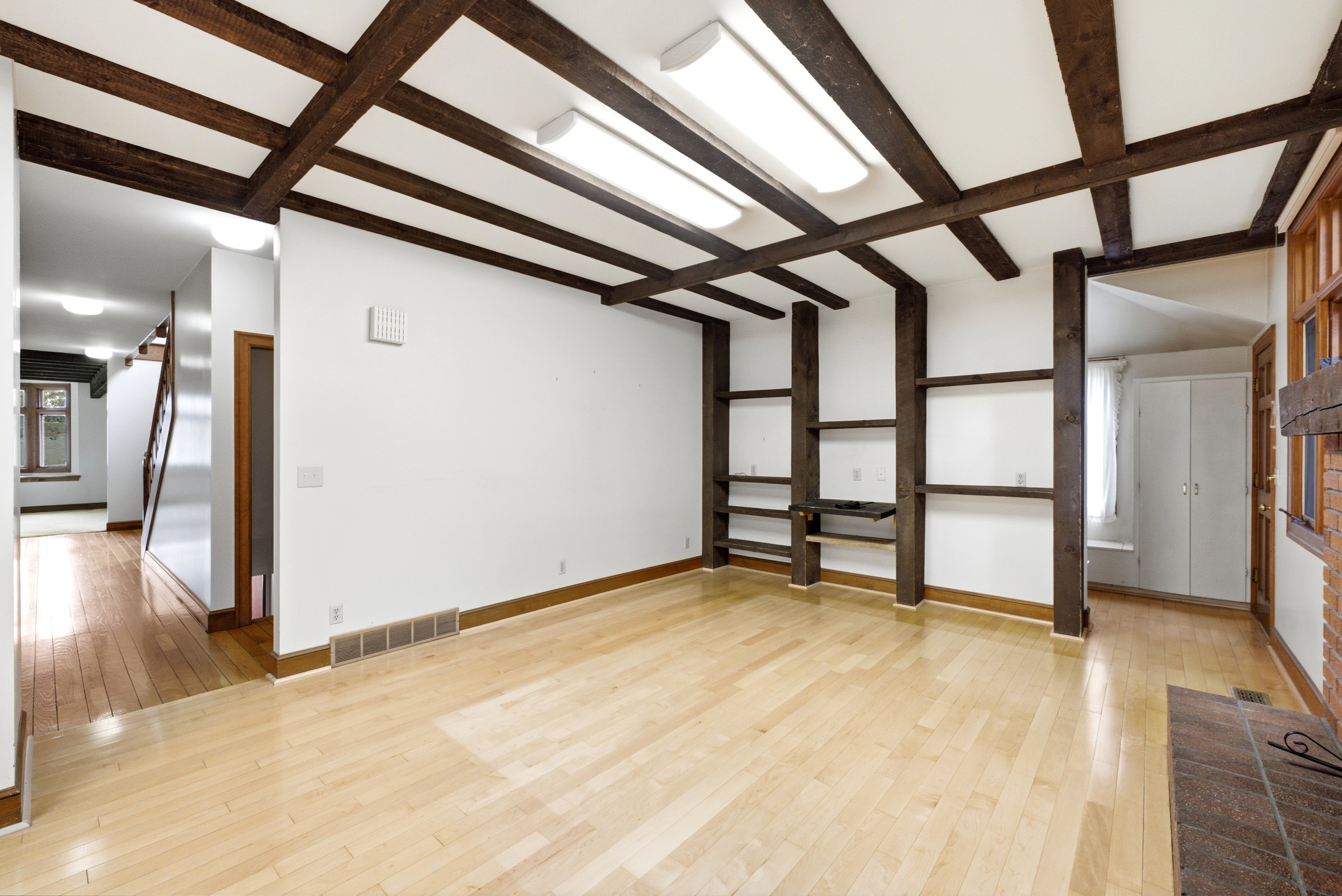 Open concept living area featuring exposed wood beams and light wood-finish flooring