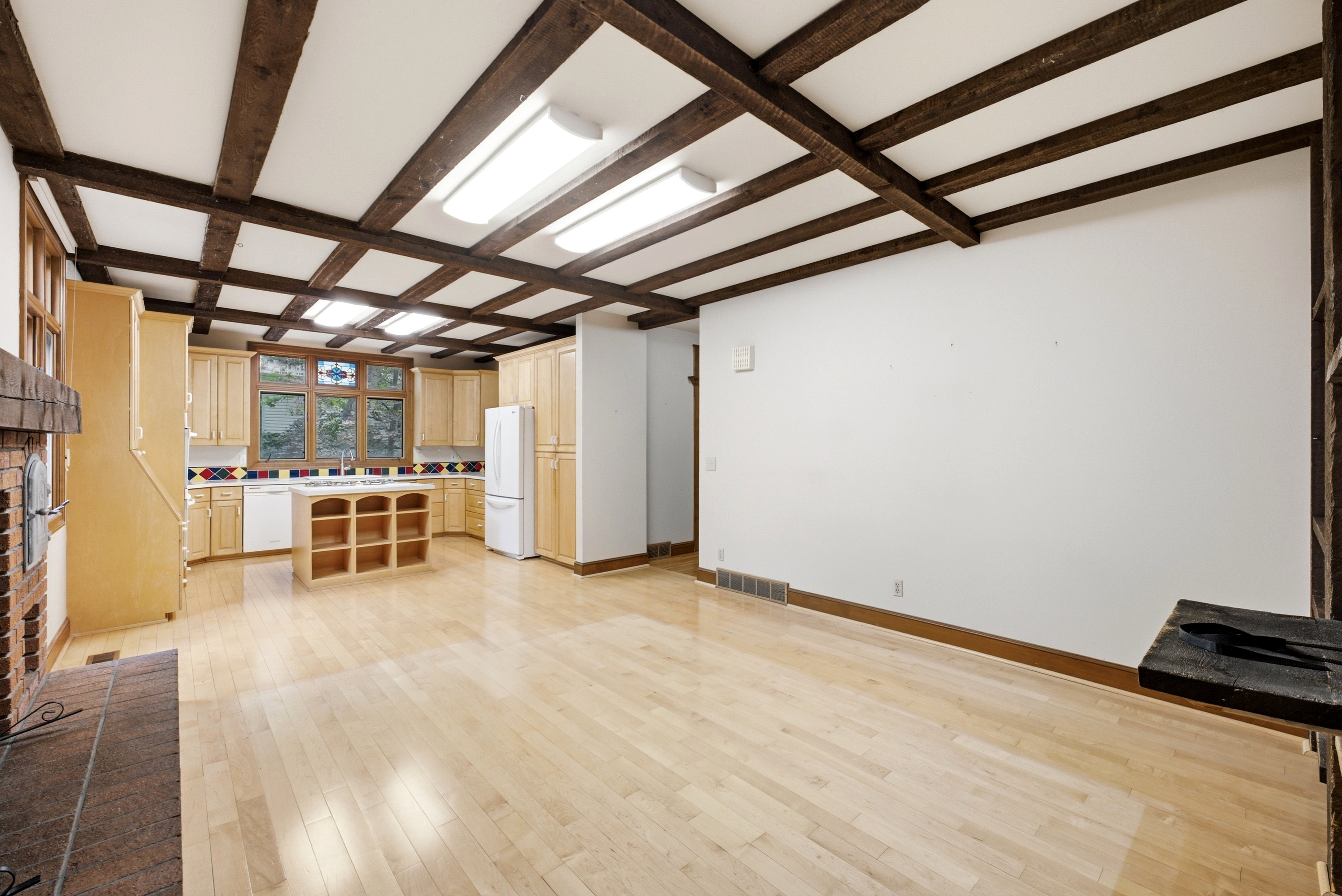 Open-concept space featuring a wood-finish floor and exposed beam ceiling