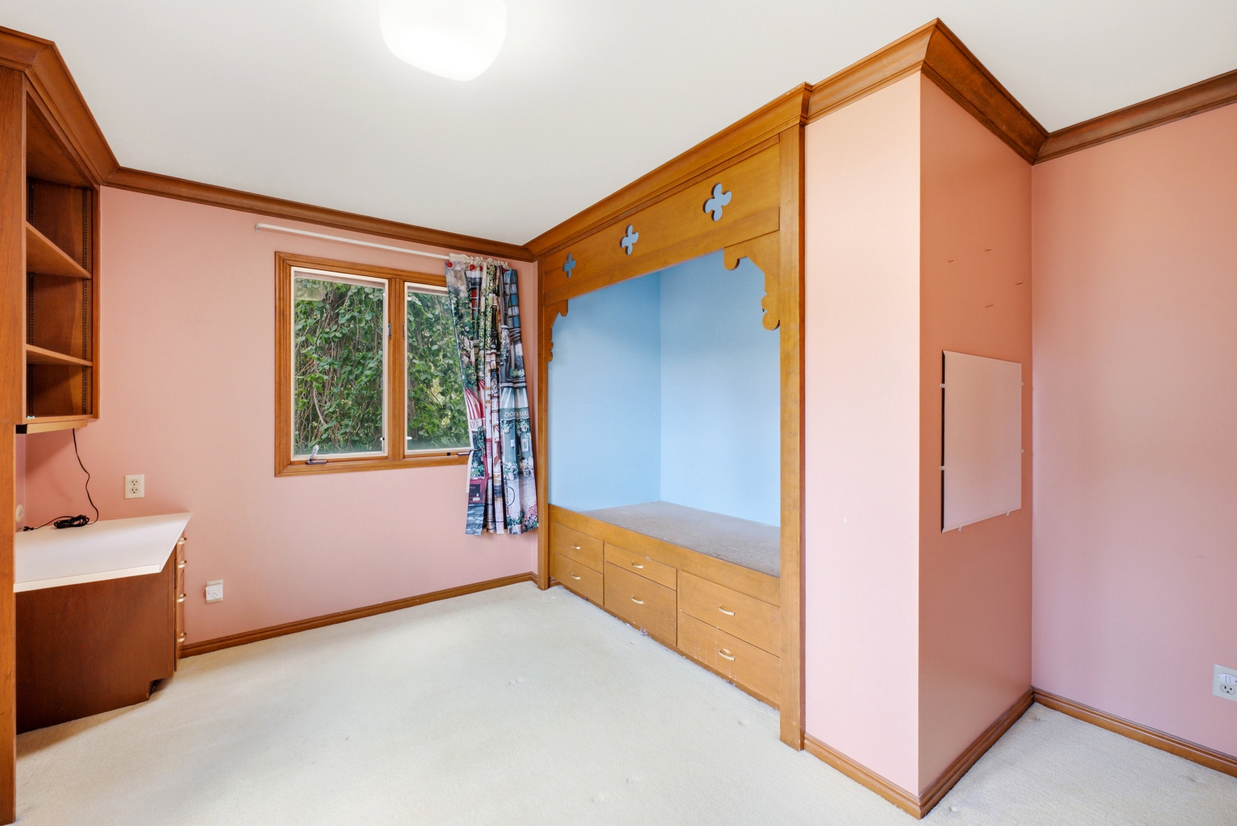 Built-in bed nook with lower drawers, hardwood trim, and wall-mounted desk with shelving