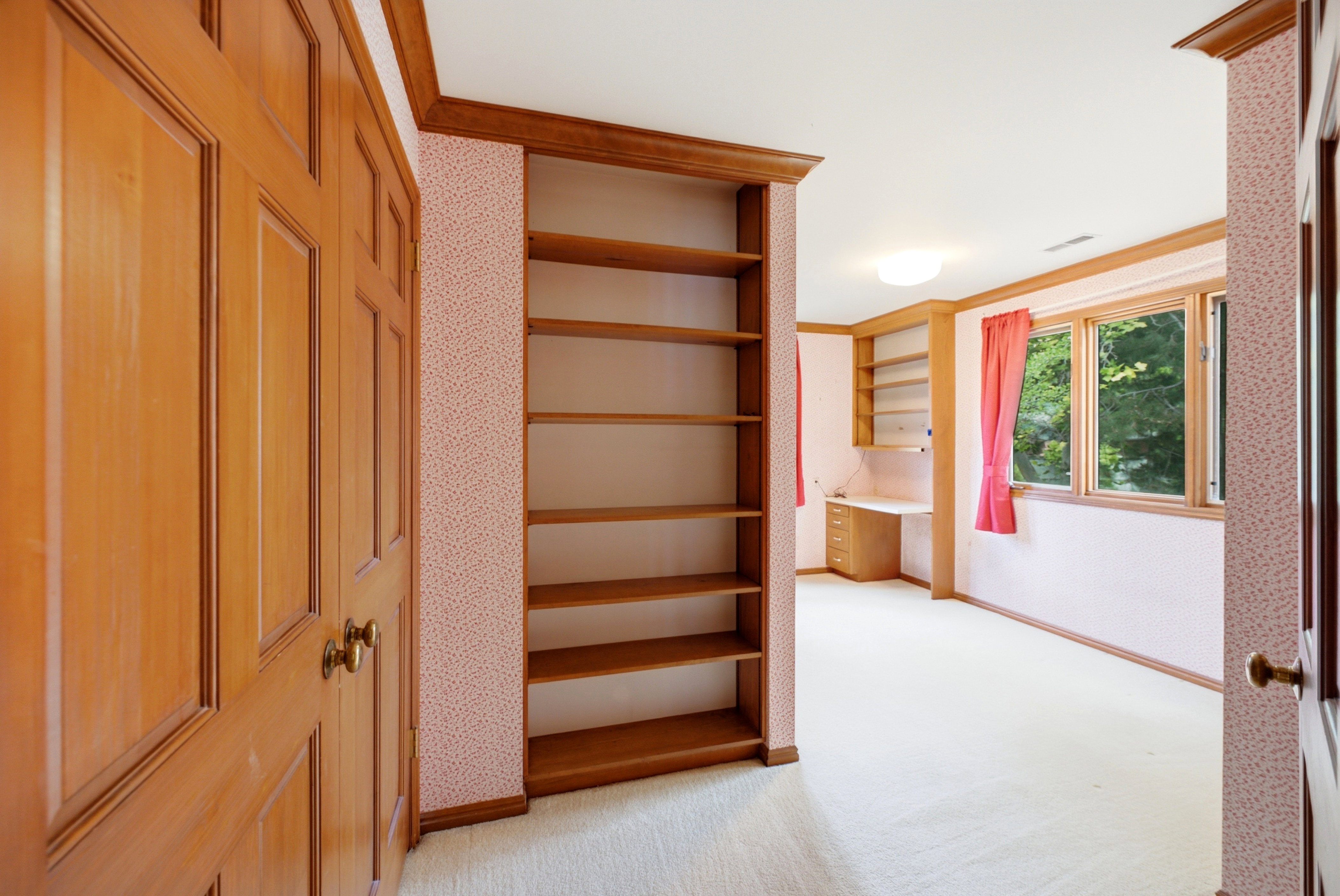 Built-in shelving and desk unit with wood-finish trim, multiple windows, and carpet flooring