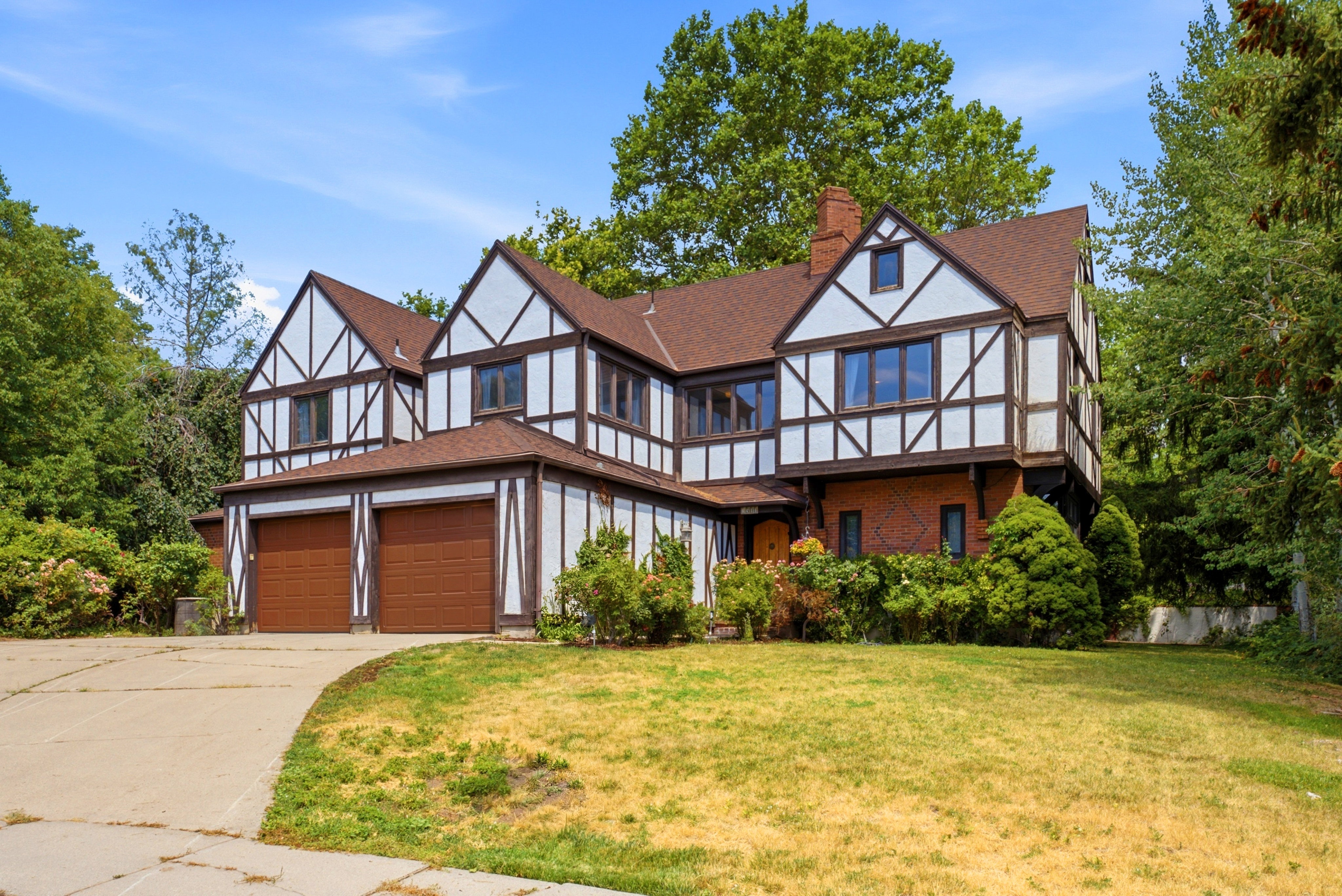 Tudor-style residence featuring a prominent front facade with white stucco and dark wood trim