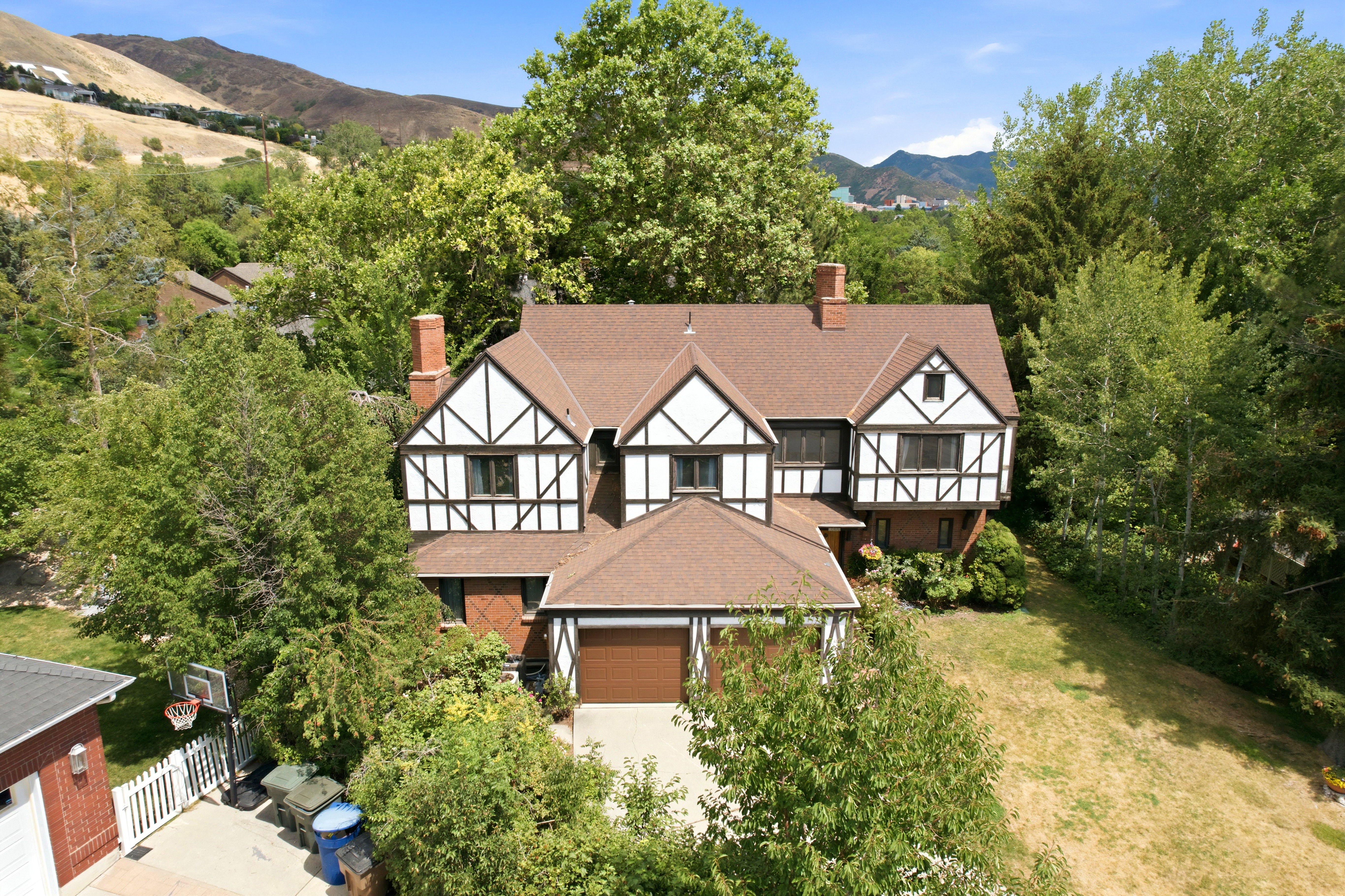Tudor Revival residence featuring a brown shingle roof, white stucco, and dark timbering accents