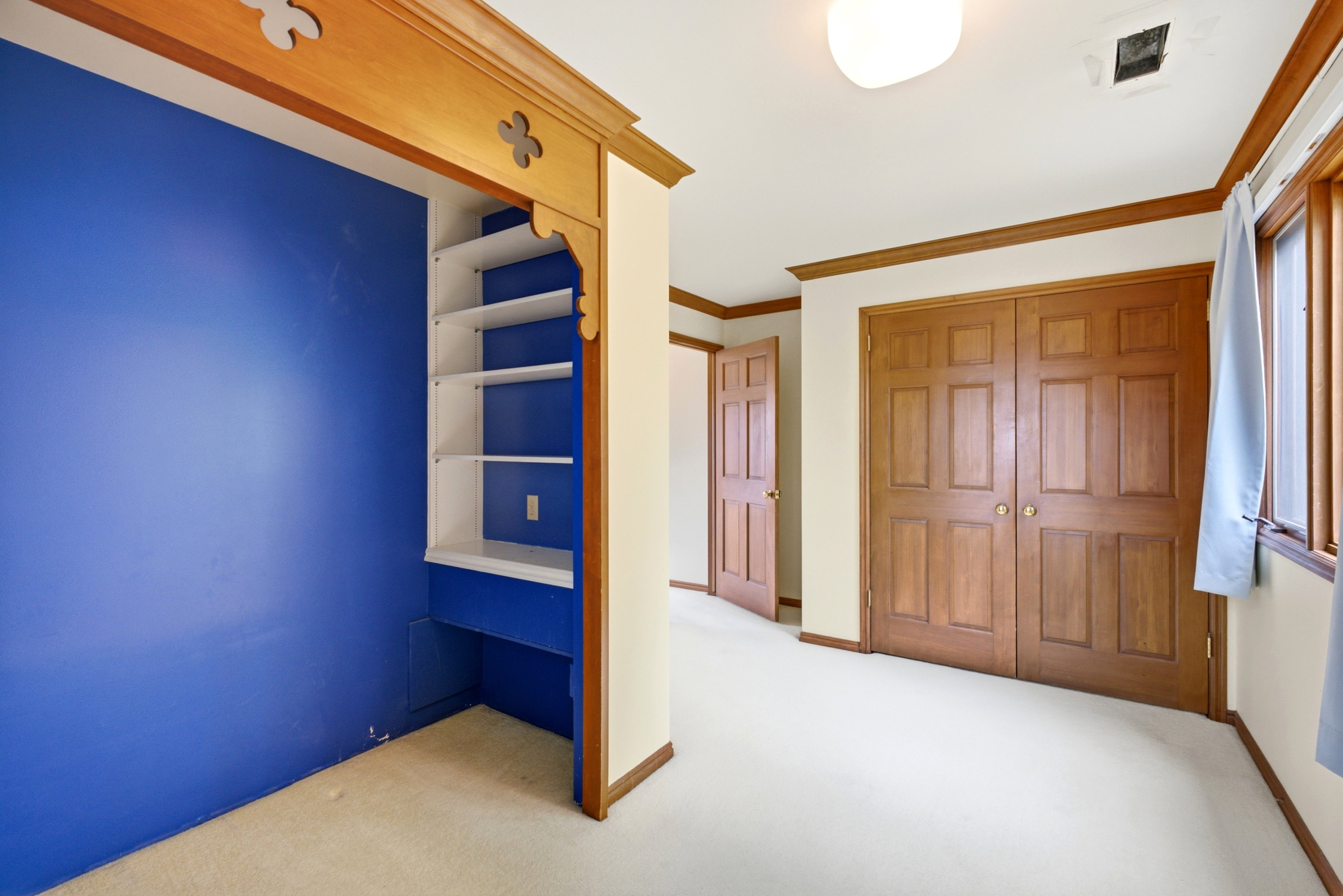 Built-in shelving with a desk area, warm wood trim, panel doors, and neutral carpet