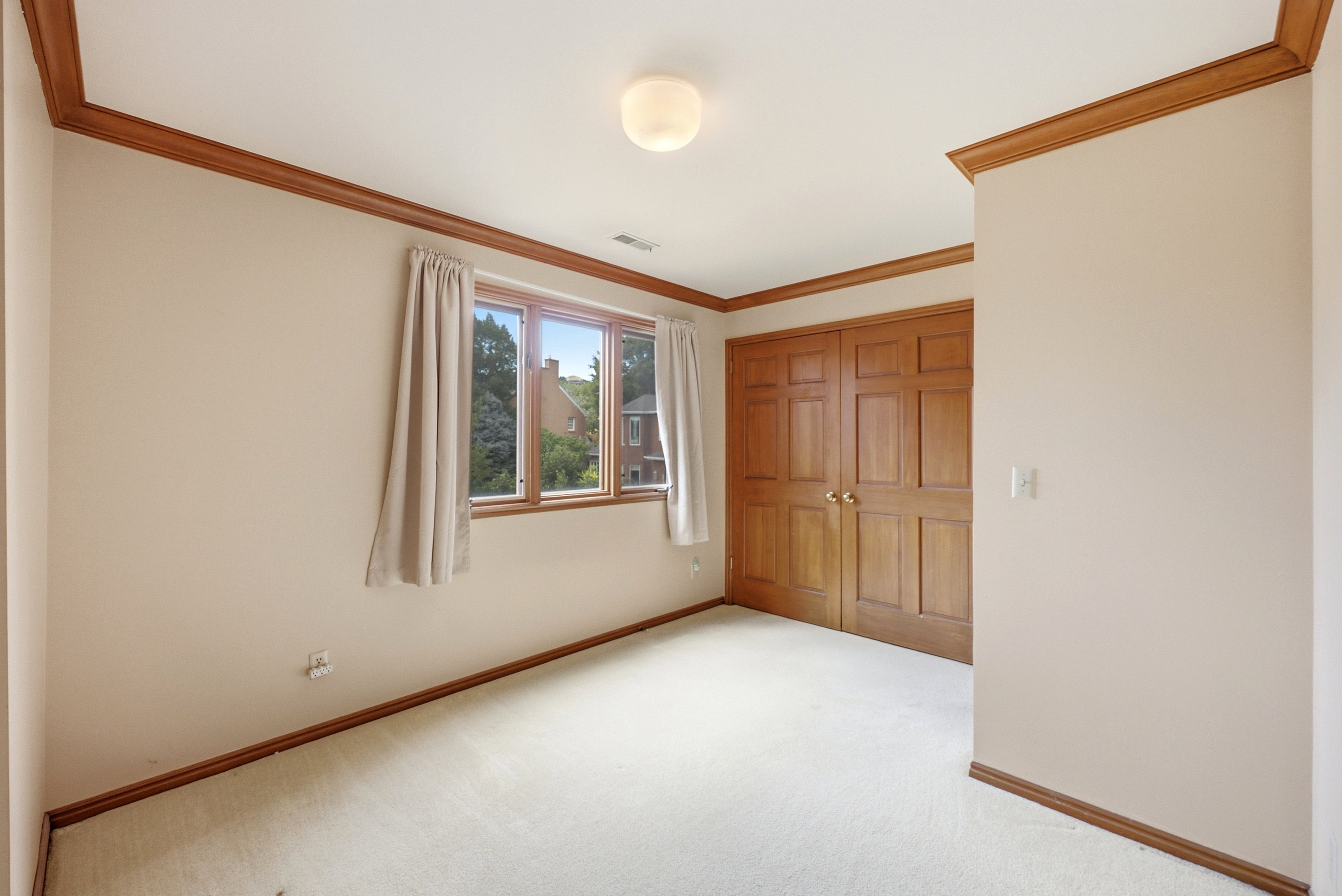 Carpeted room with a multi-pane window, neutral wall finishes, and wood trim