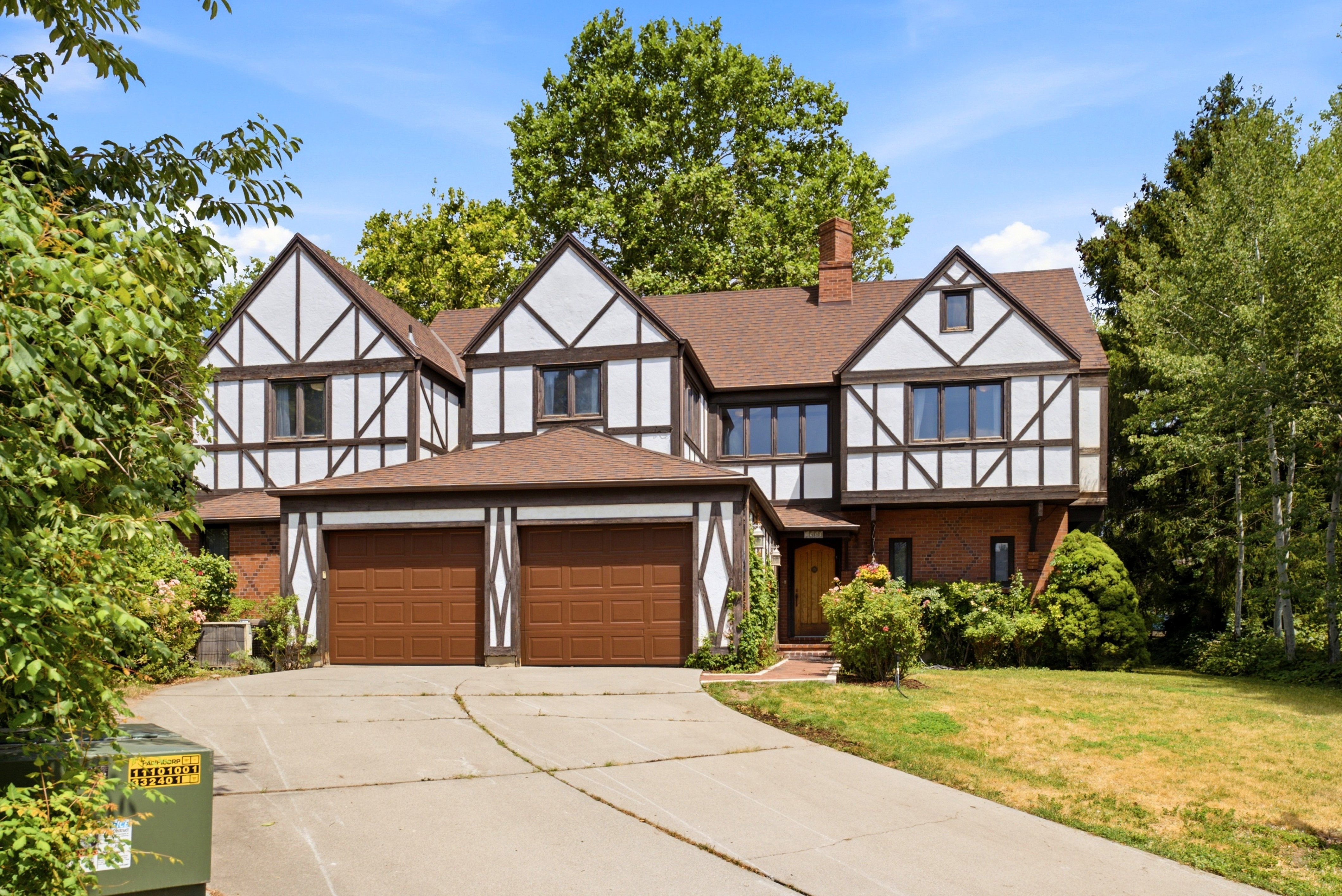 Tudor-style residence featuring a prominent brown roof and white exterior with dark timber framing