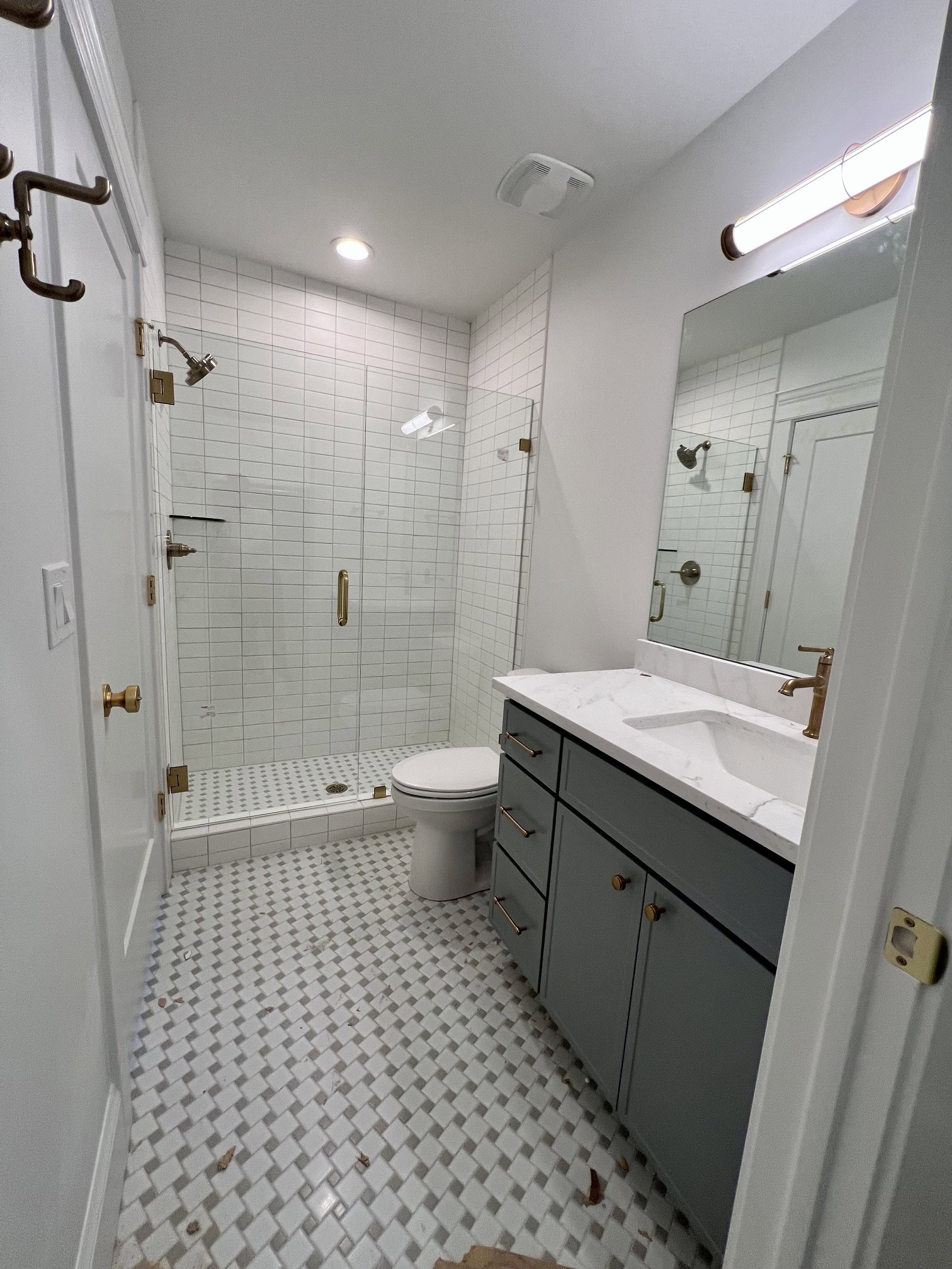 Bathroom featuring a glass-enclosed shower with subway tile surround, a single vanity with a white countertop and undermount sink, and decorative floor tiling