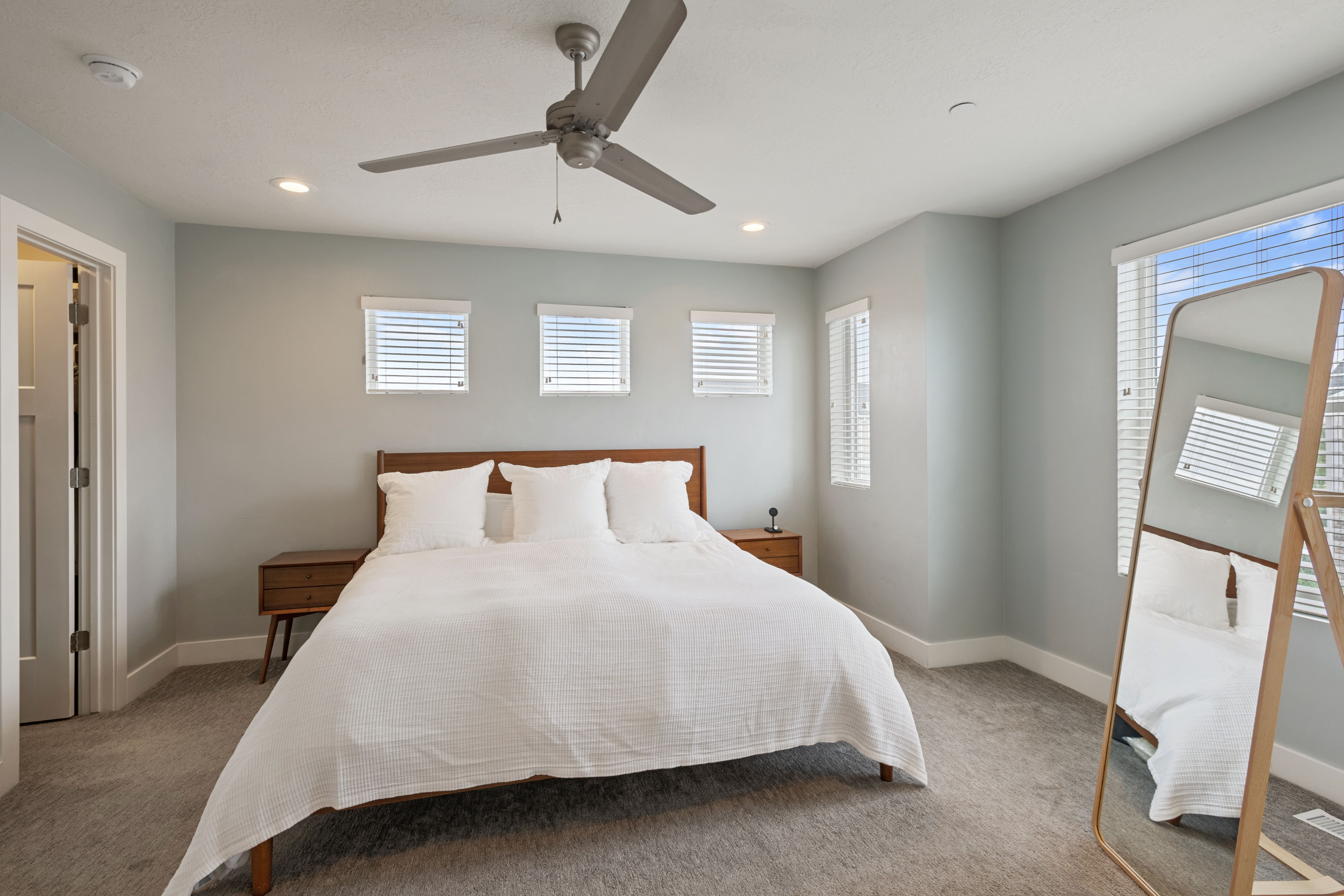 Spacious room featuring light gray carpeting, neutral wall color, recessed lighting, and a ceiling fan