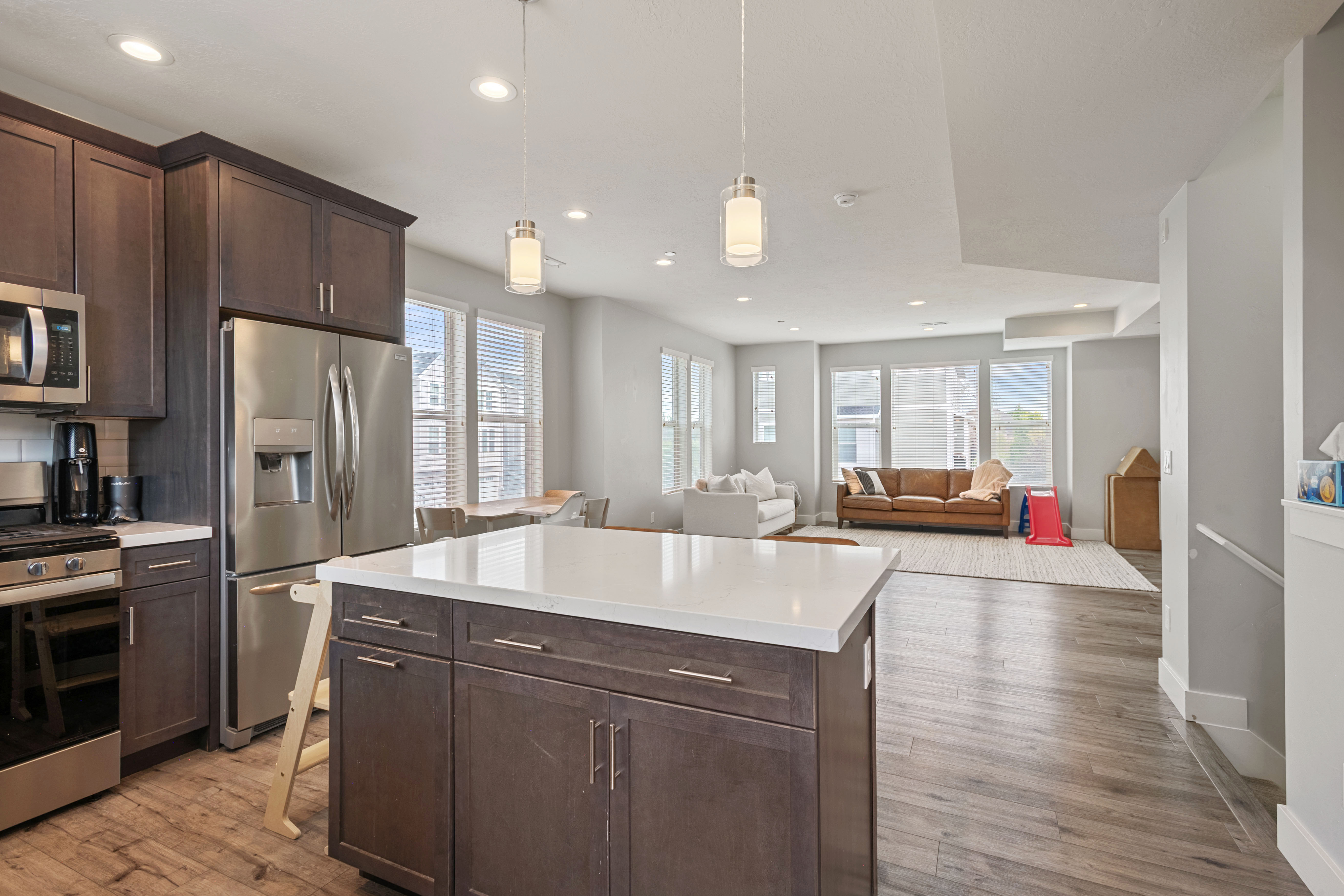 Kitchen featuring dark wood-finish cabinetry, stainless steel appliances, a white subway tile backsplash, and a large island with a white countertop