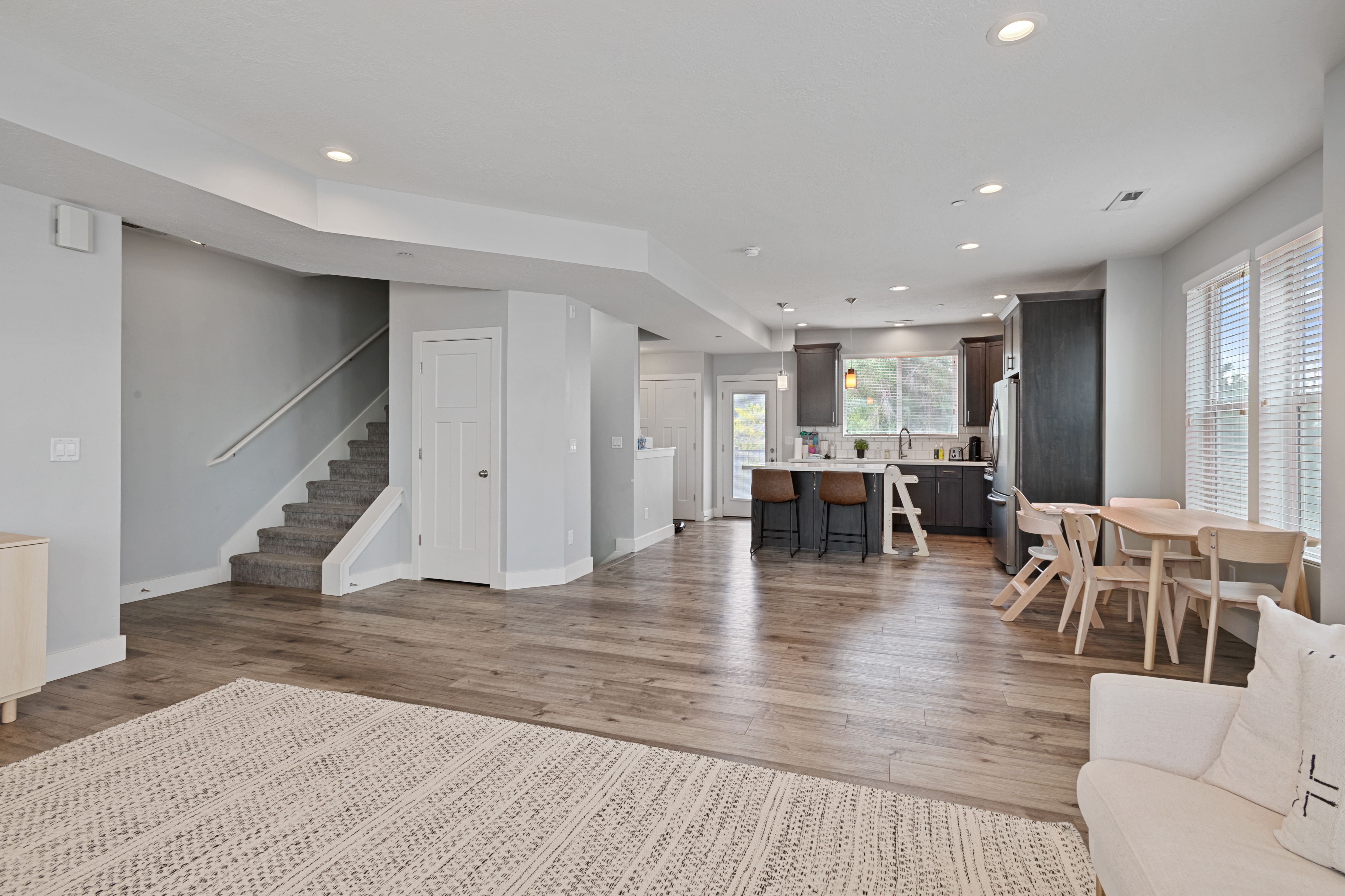 Open-concept living area featuring wood-finish flooring throughout, recessed lighting, and bright white trim