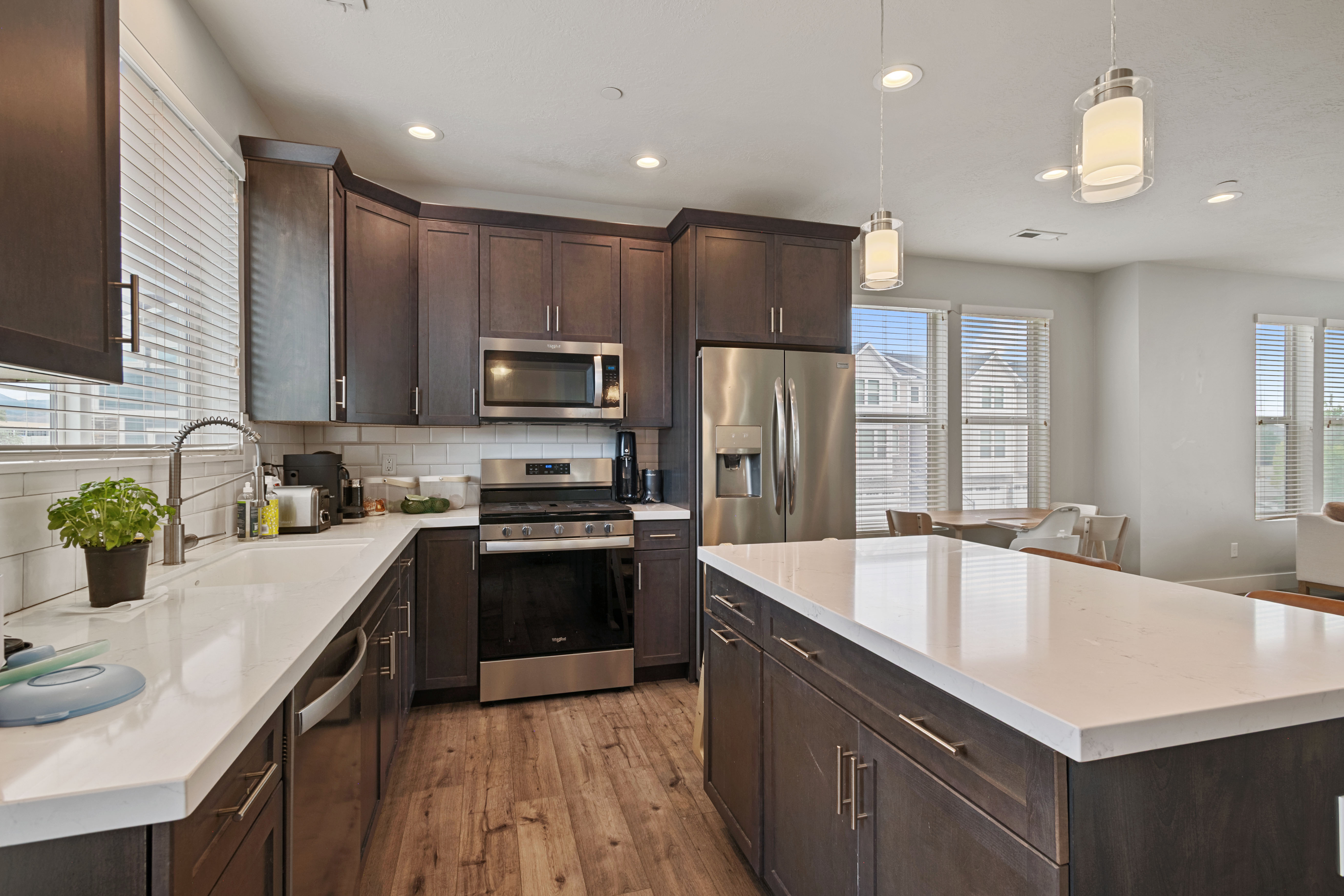 Modern kitchen featuring dark wood cabinetry, stainless steel appliances, white countertops, and a subway tile backsplash
