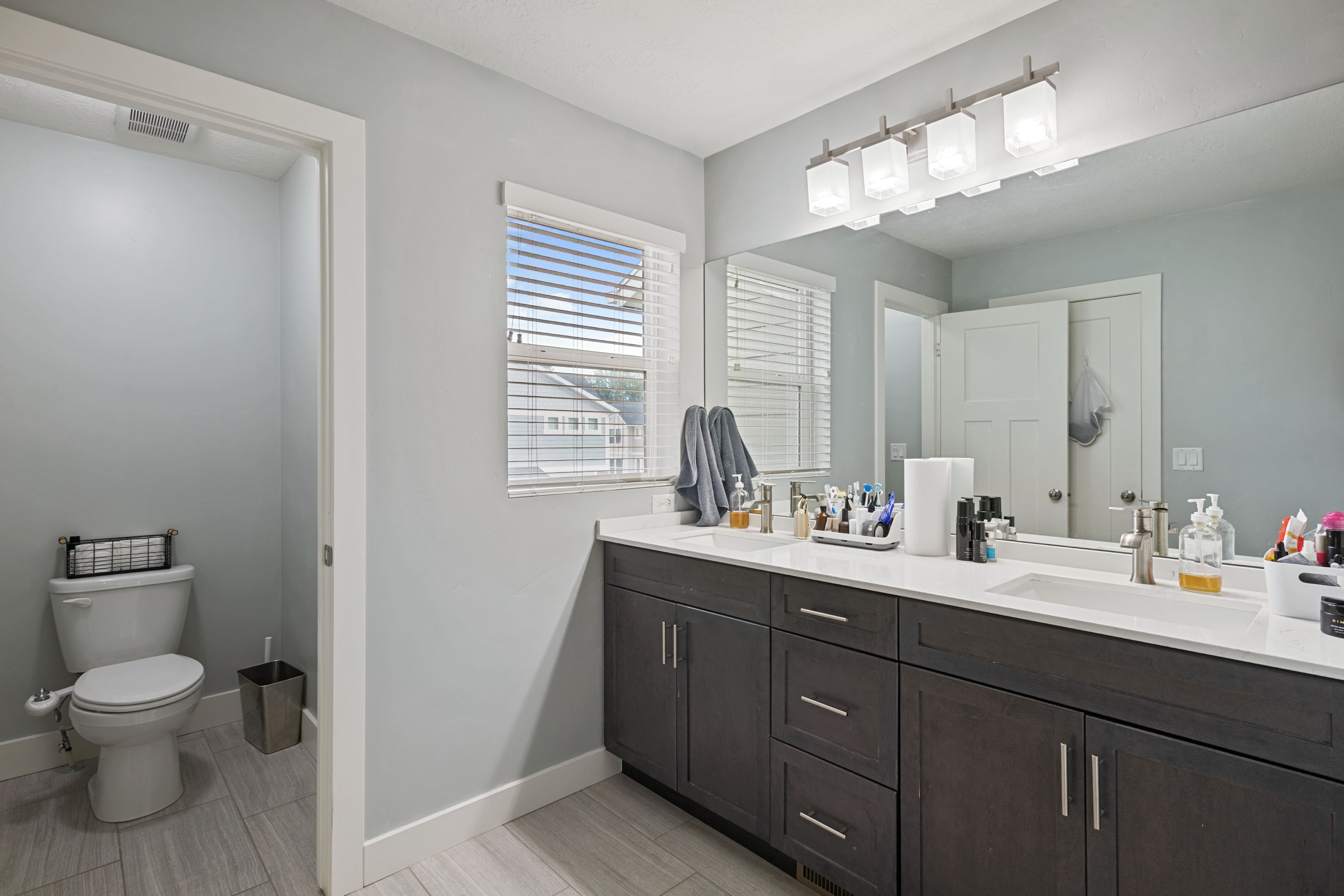 Bathroom featuring a double vanity with dark wood-finish cabinetry, white countertops, and dual undermount sinks