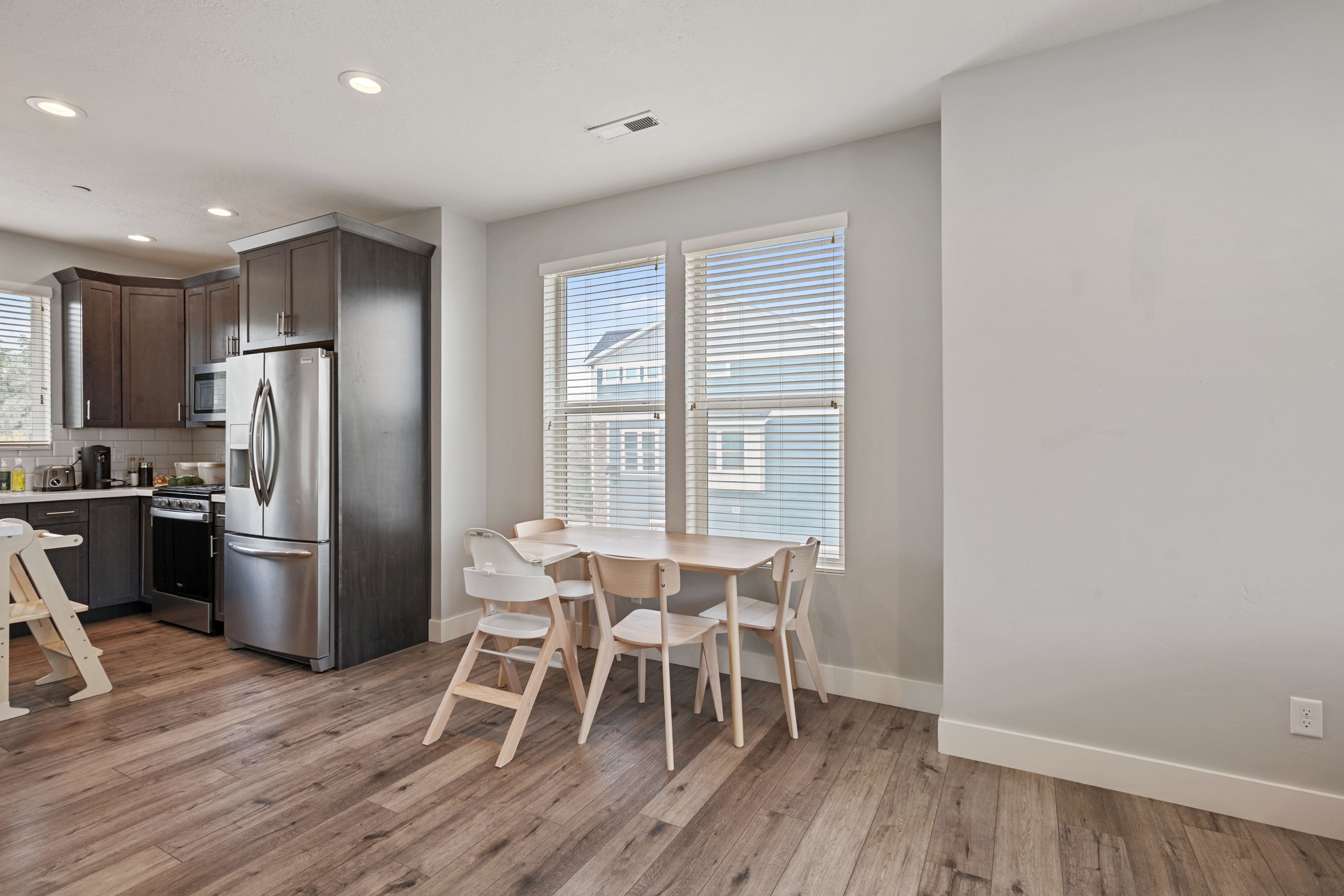 Open-concept kitchen and dining area featuring wood-finish flooring, recessed lighting, and a neutral color palette