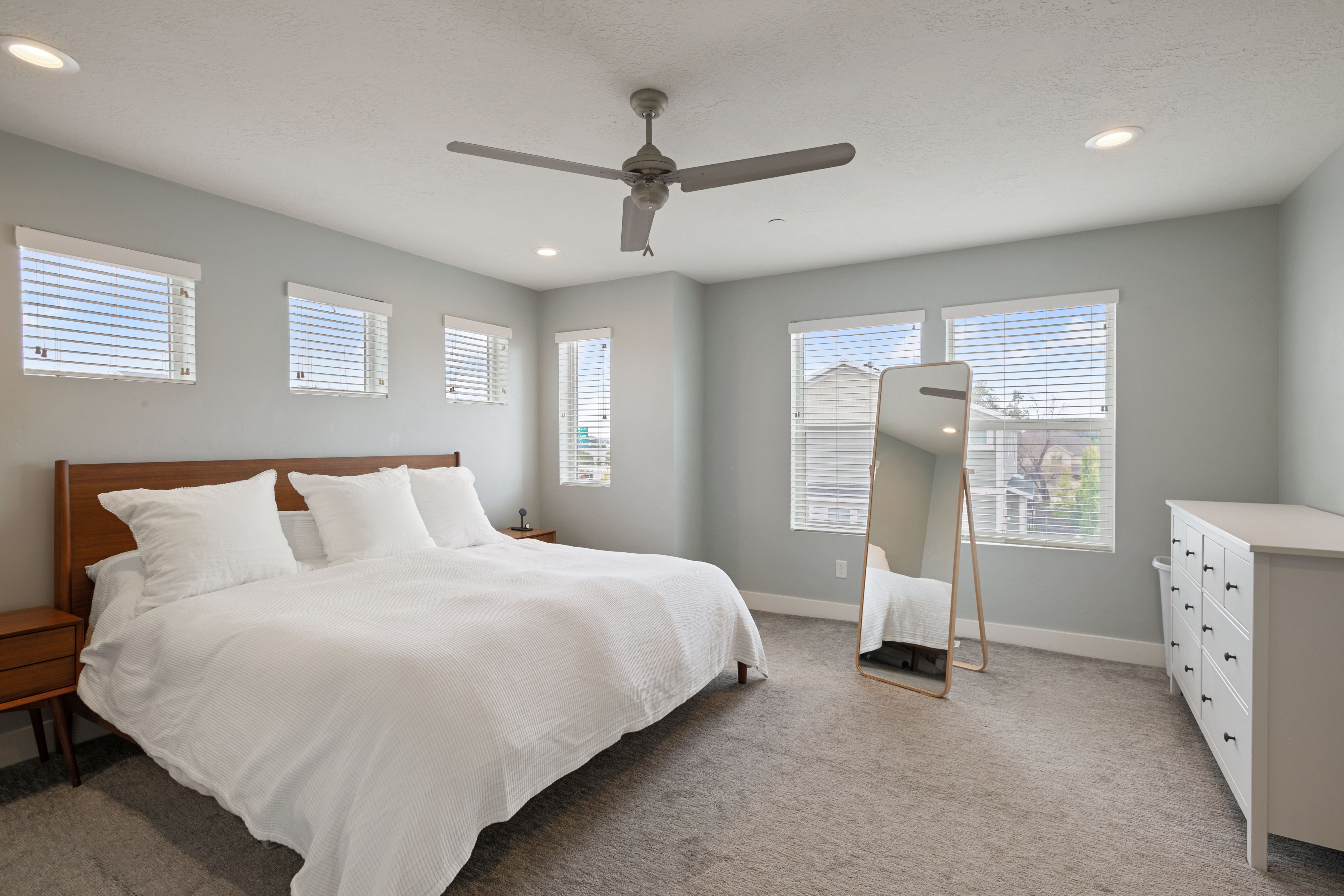 Carpeted room with multiple windows featuring blinds, recessed lighting, and a ceiling fan