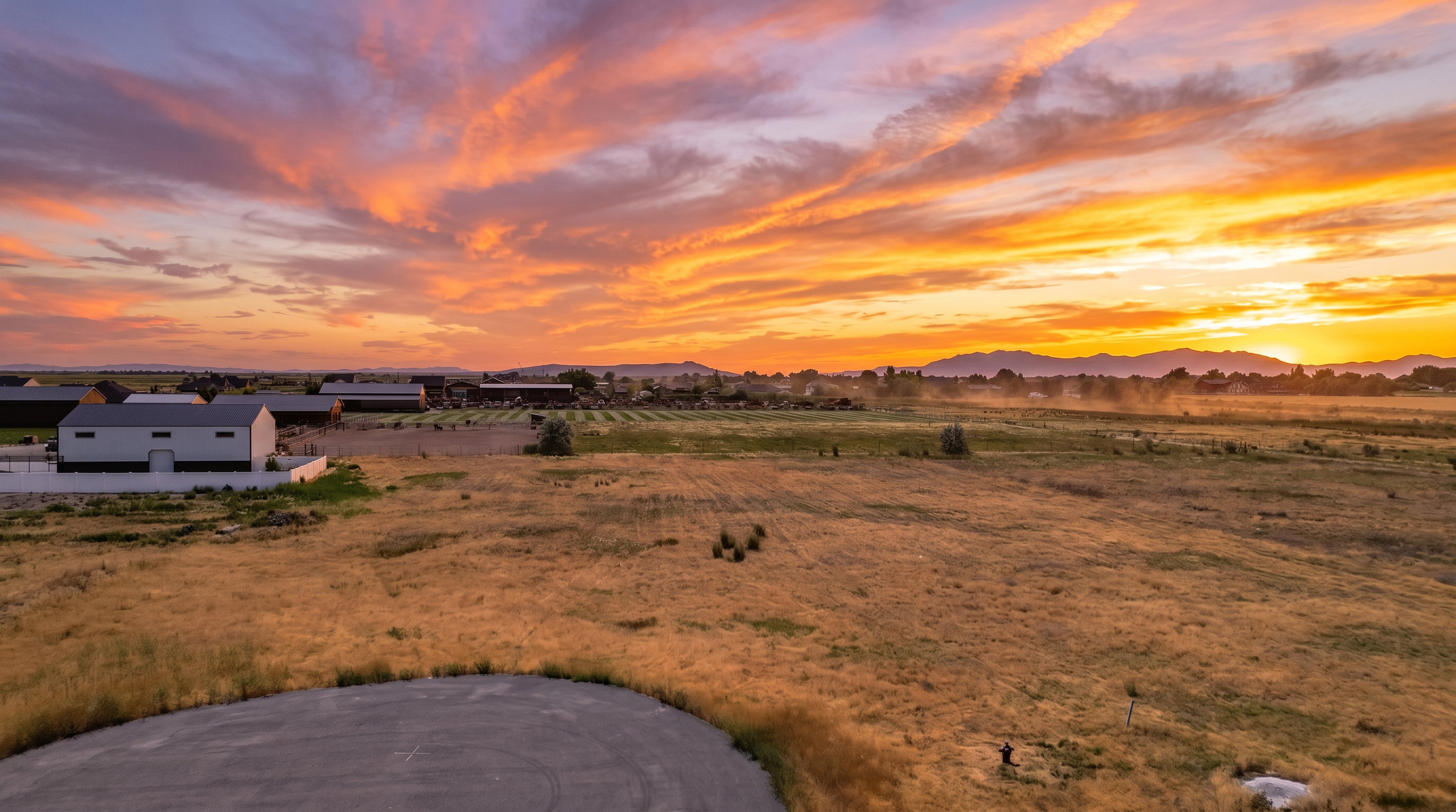 Expansive lot featuring a wide-open field of natural grass and a partial paved area