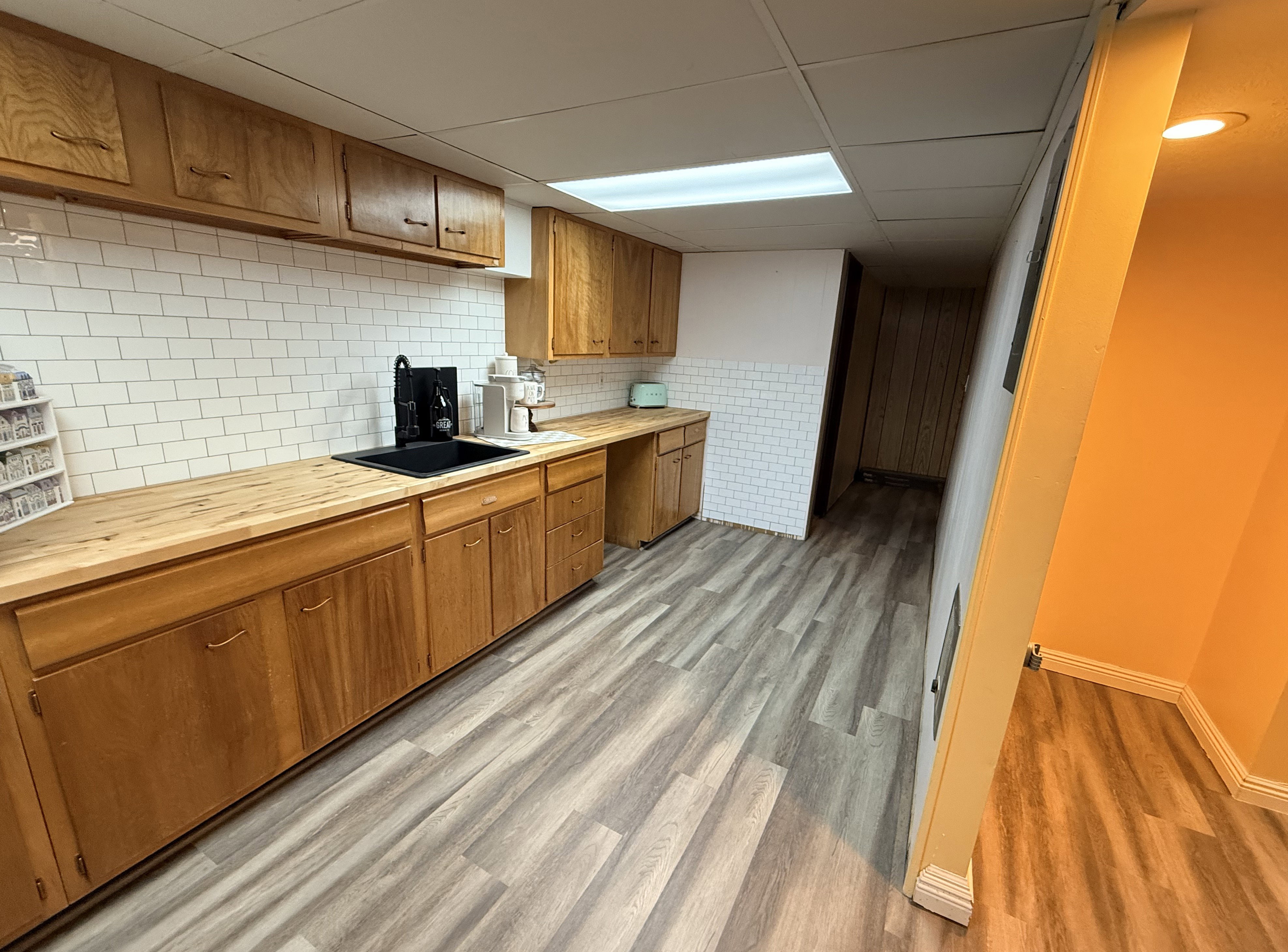 Kitchenette featuring extensive wood cabinetry, wood-finish countertops, and a white subway tile backsplash